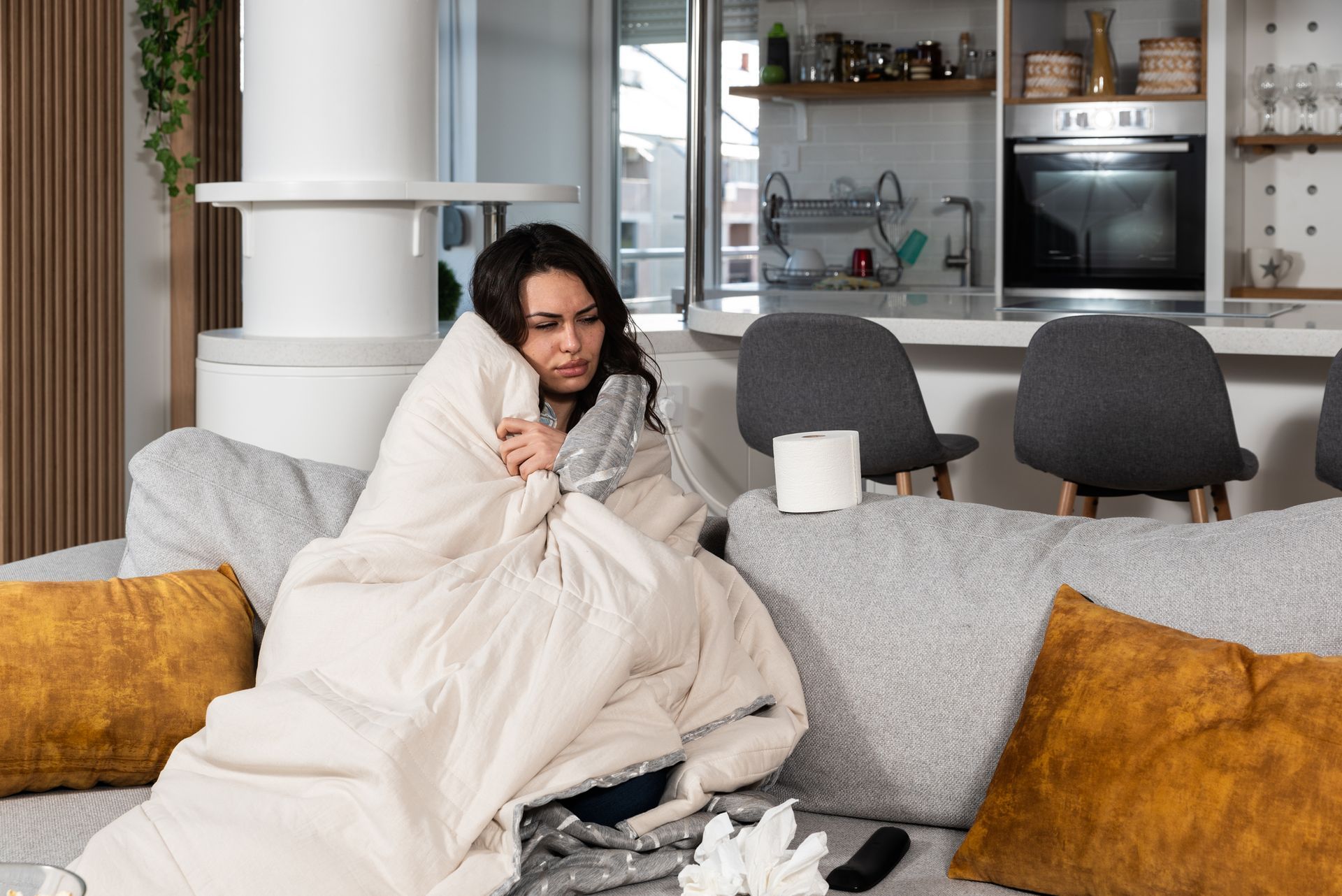 Young woman wrapped in a blanket and needs heat pump repairs.