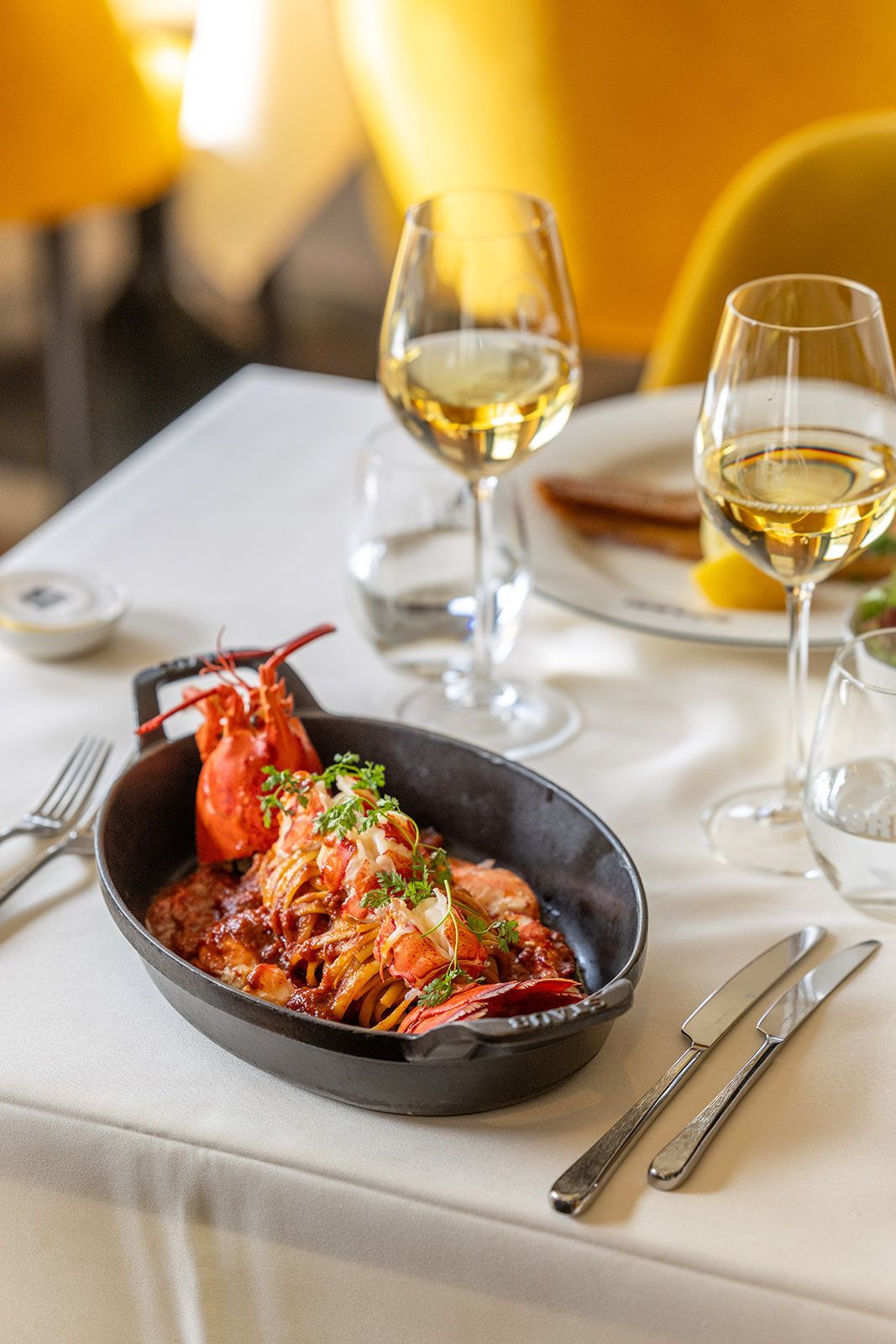 Interior view of a modern bar with a backlit shelf of various bottles and two bottles in the foreground.