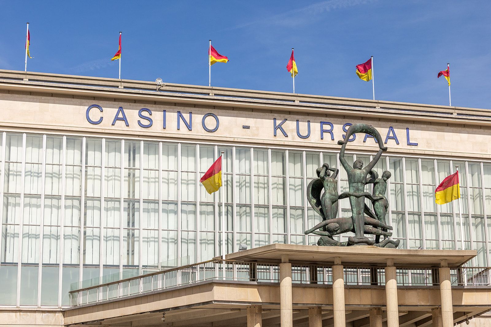 A dining area viewed through a doorway, featuring a round table, two bright yellow velvet chairs, and a stone fireplace.