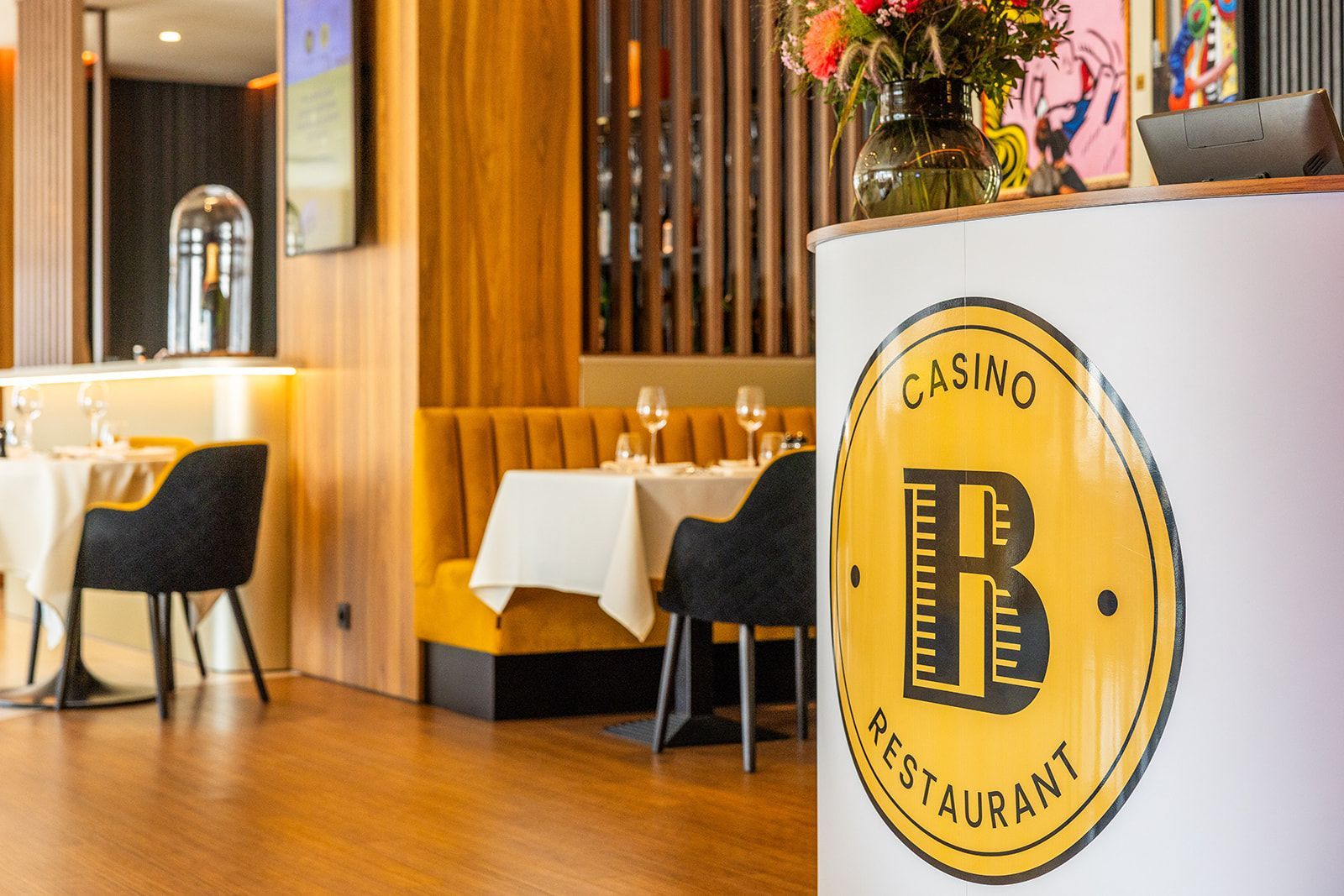 Modern restaurant dining area with white tablecloths, dark chairs, and a yellow 