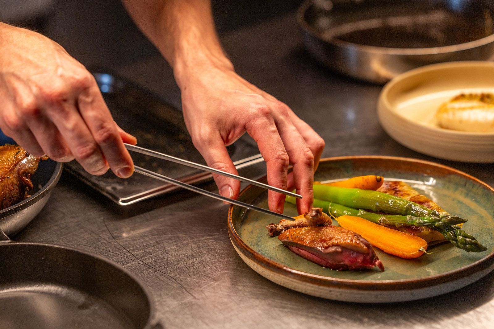 A dining area viewed through a doorway, featuring a round table, two bright yellow velvet chairs, and a stone fireplace.