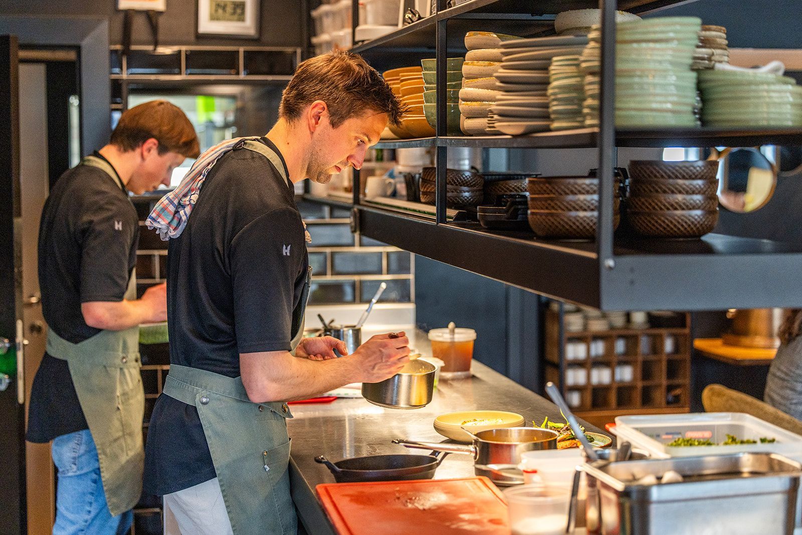 A white door frame looking into a room with a dark-wood fireplace, a dining table with yellow chairs, and tiled floors.