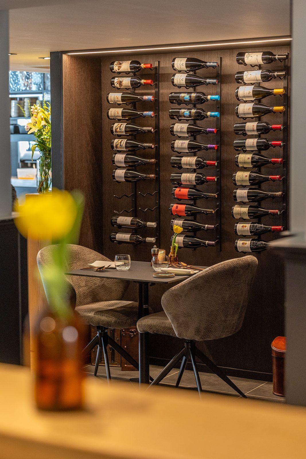 Interior view of a modern bar with a backlit shelf of various bottles and two bottles in the foreground.