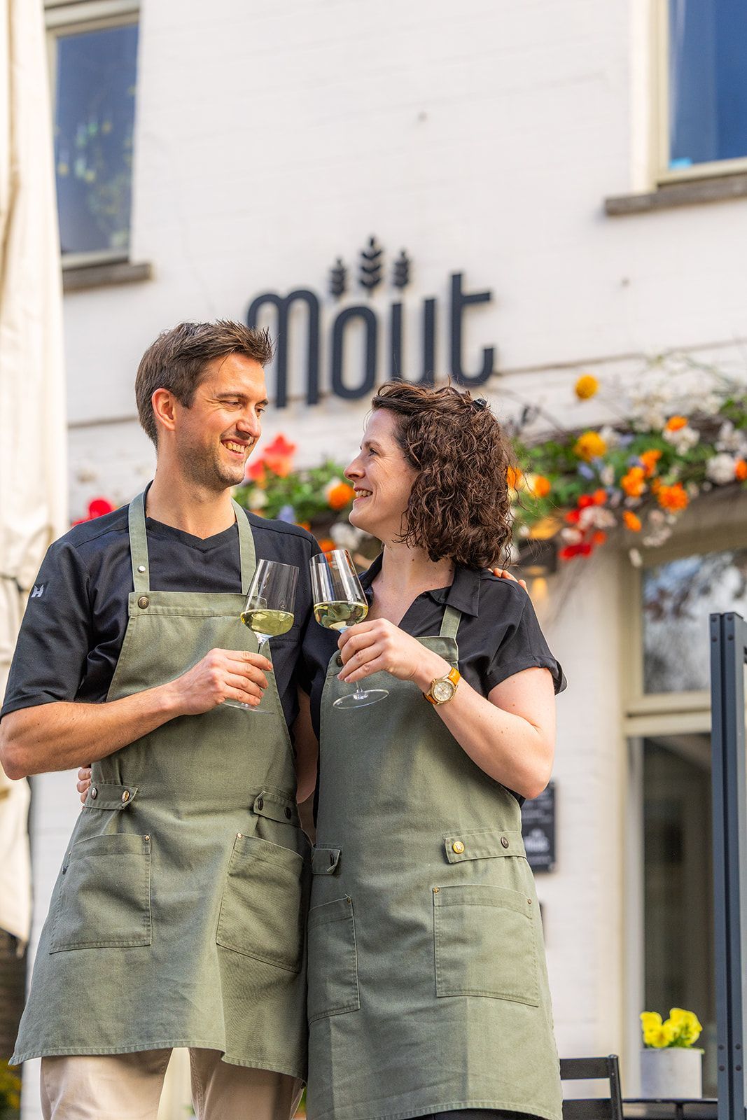 A bright, modern restaurant with wood floors, exposed brick, large windows, and yellow upholstered chairs at tables.