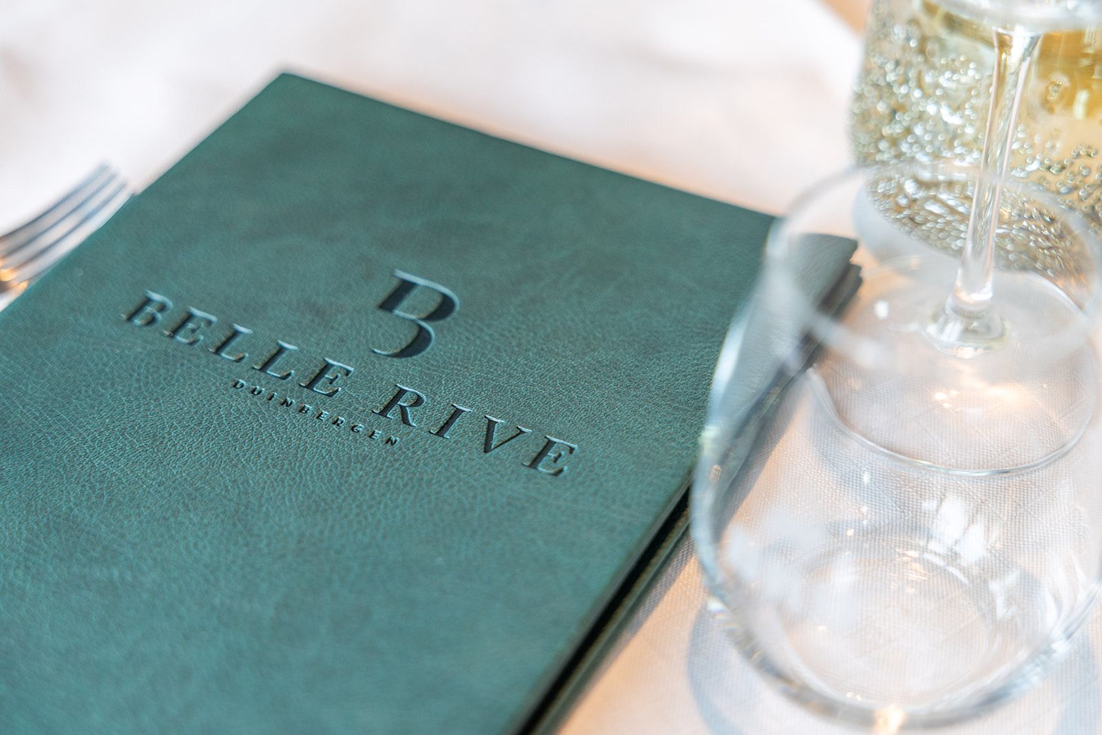 A white two-story brick building with a dark sculpture in the front yard featuring the text