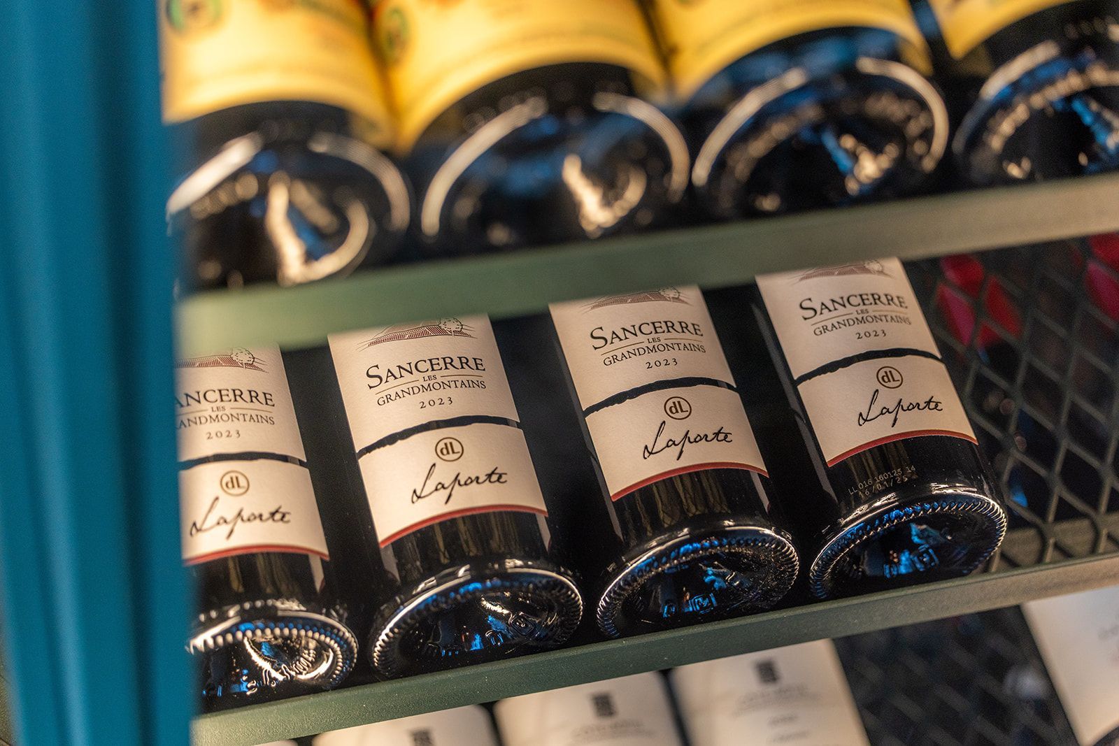Interior view of a modern bar with a backlit shelf of various bottles and two bottles in the foreground.