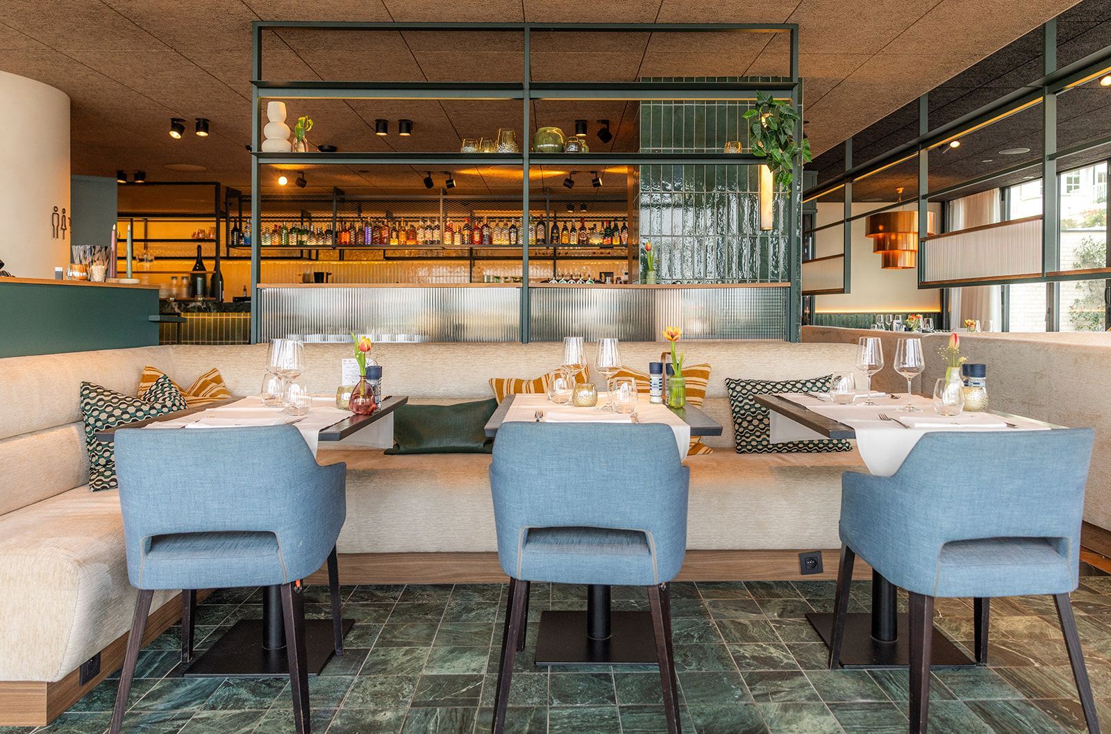 An outdoor restaurant patio with glass walls and tables, featuring the text 
