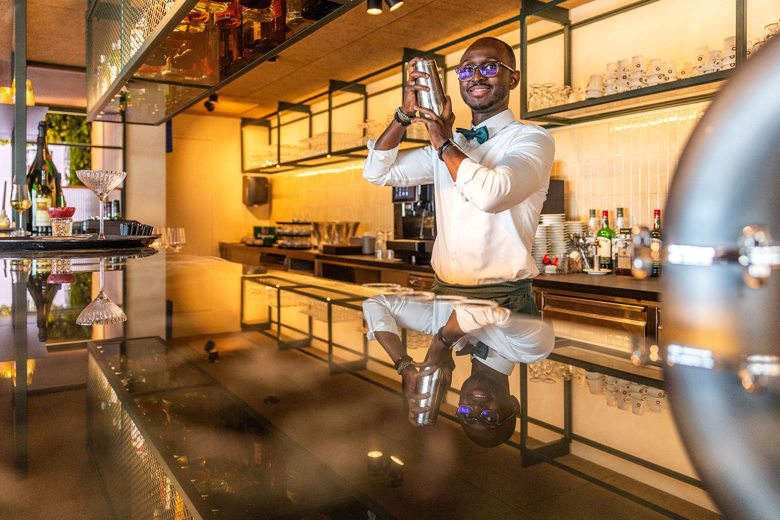 Outdoor restaurant seating with white-clothed tables, chairs, and a large black-and-white portrait of men in tuxedos.