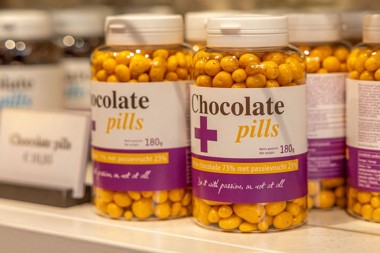 A restaurant interior featuring round tables with yellow chairs, a dark blue wall with a round gold light, and patterned tiles.