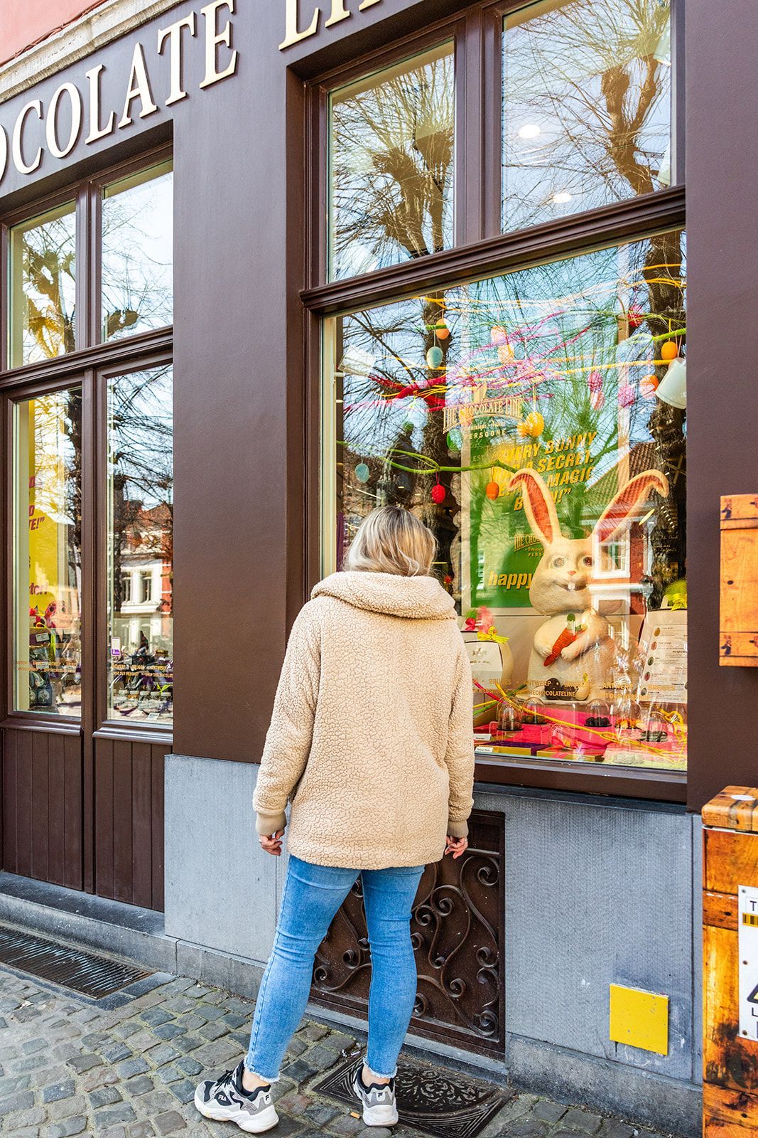 A white door frame looking into a room with a dark-wood fireplace, a dining table with yellow chairs, and tiled floors.