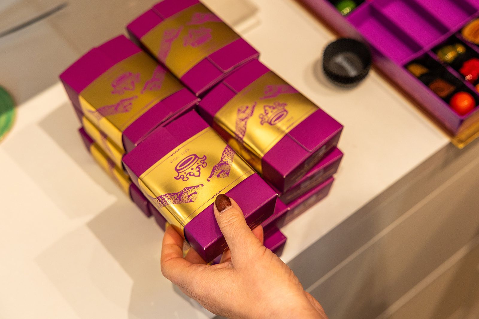 A dining area viewed through a doorway, featuring a round table, two bright yellow velvet chairs, and a stone fireplace.