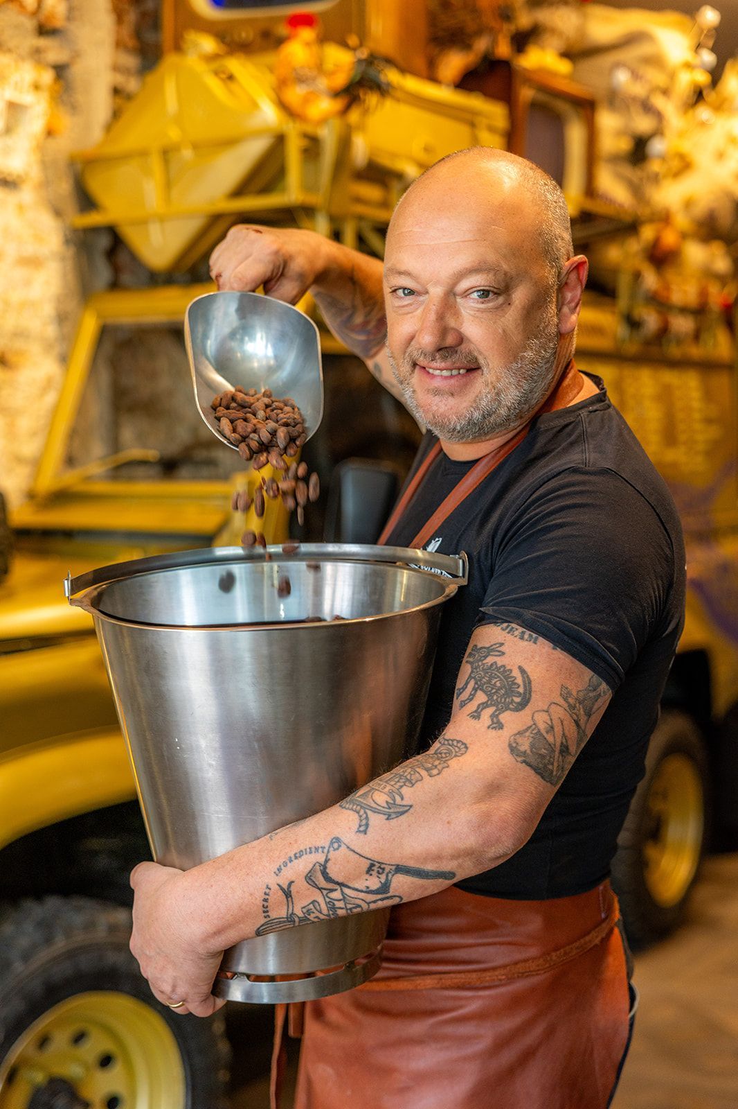 A bright, modern restaurant with wood floors, exposed brick, large windows, and yellow upholstered chairs at tables.