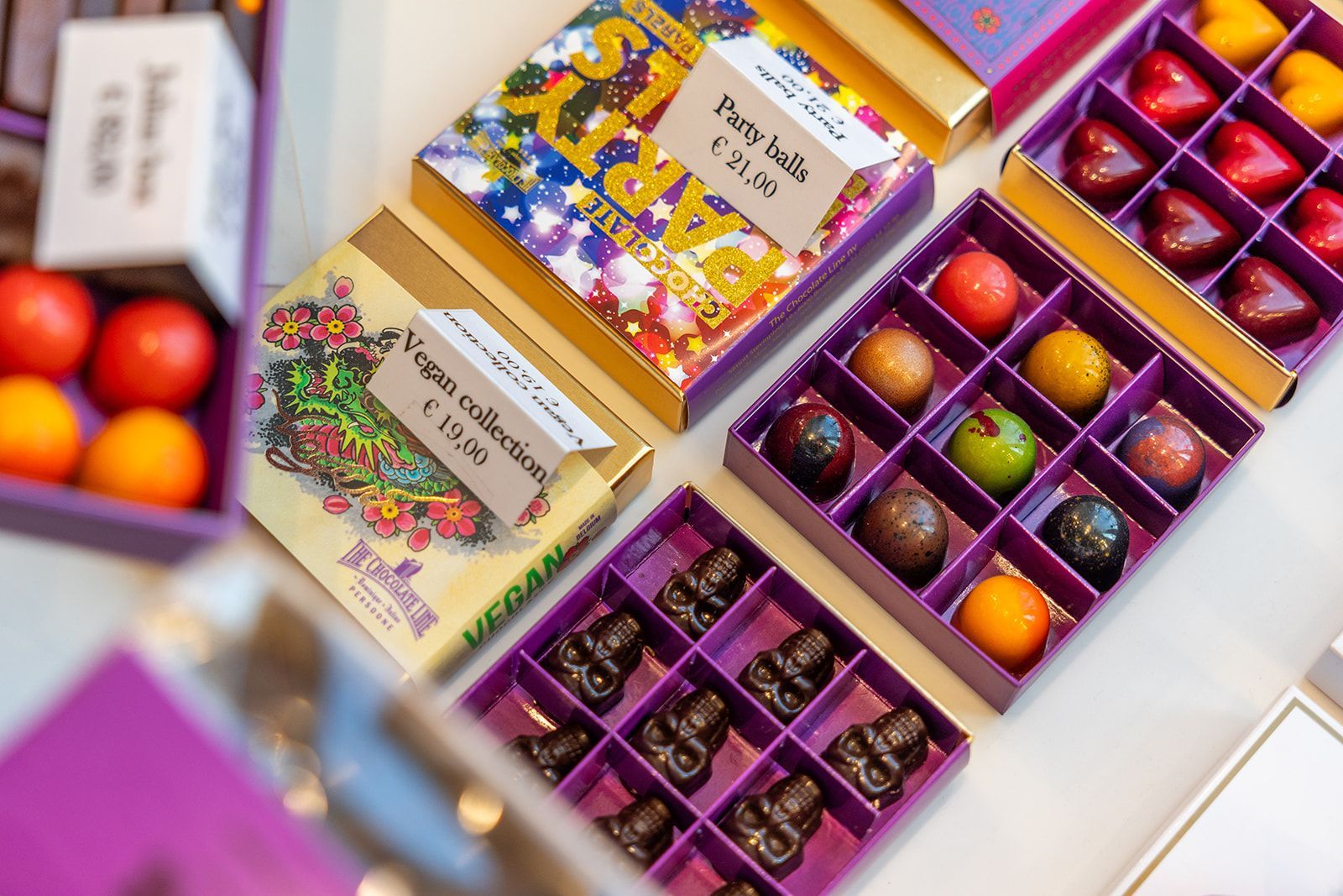 Three smiling staff members in patterned blouses or a shirt and grey aprons stand together inside a brick-walled space.