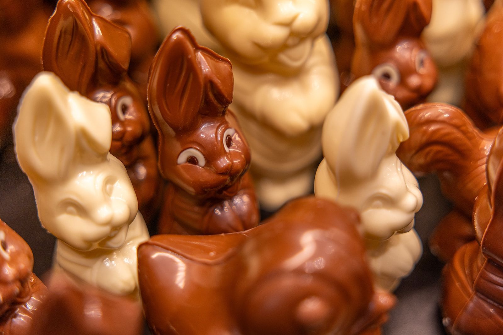 A table set for dining in a restaurant with exposed brick walls, a window overlooking a bar, and yellow and green chairs.