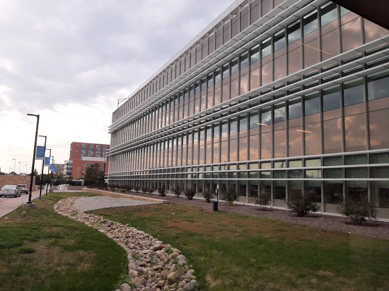 A large building with a lot of windows is surrounded by grass and rocks.