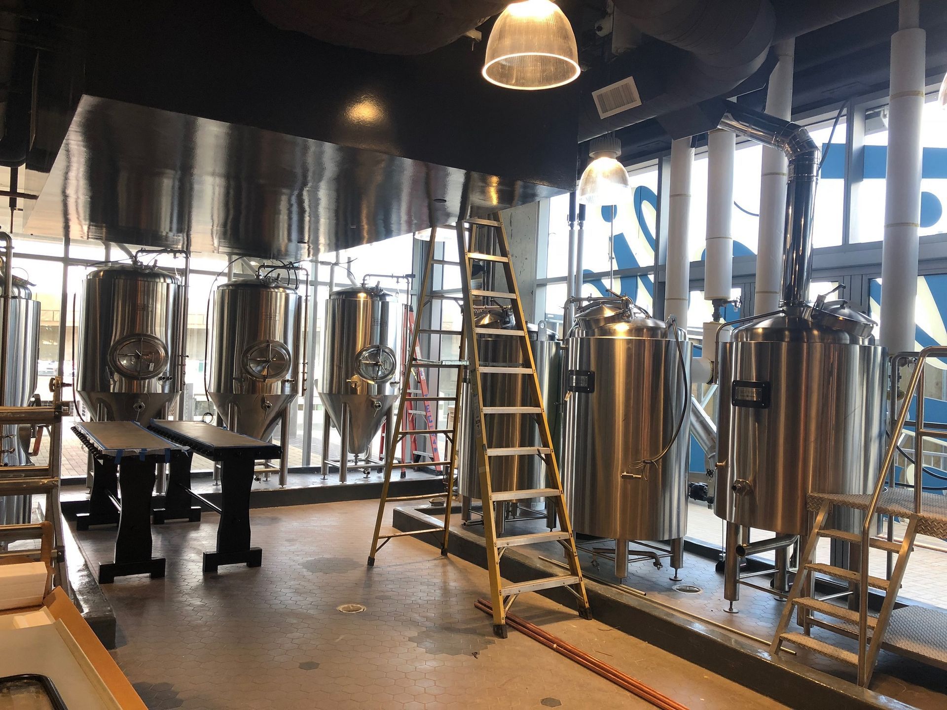 There is a ladder in the middle of the room in a brewery.