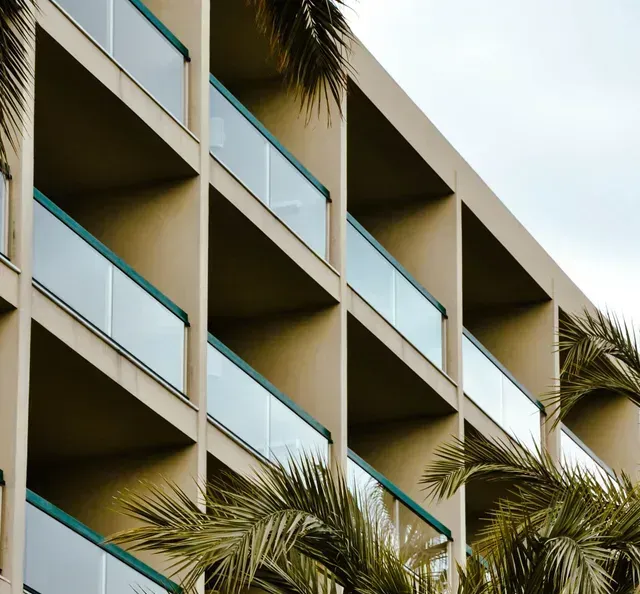A building with many balconies and palm trees in front of it