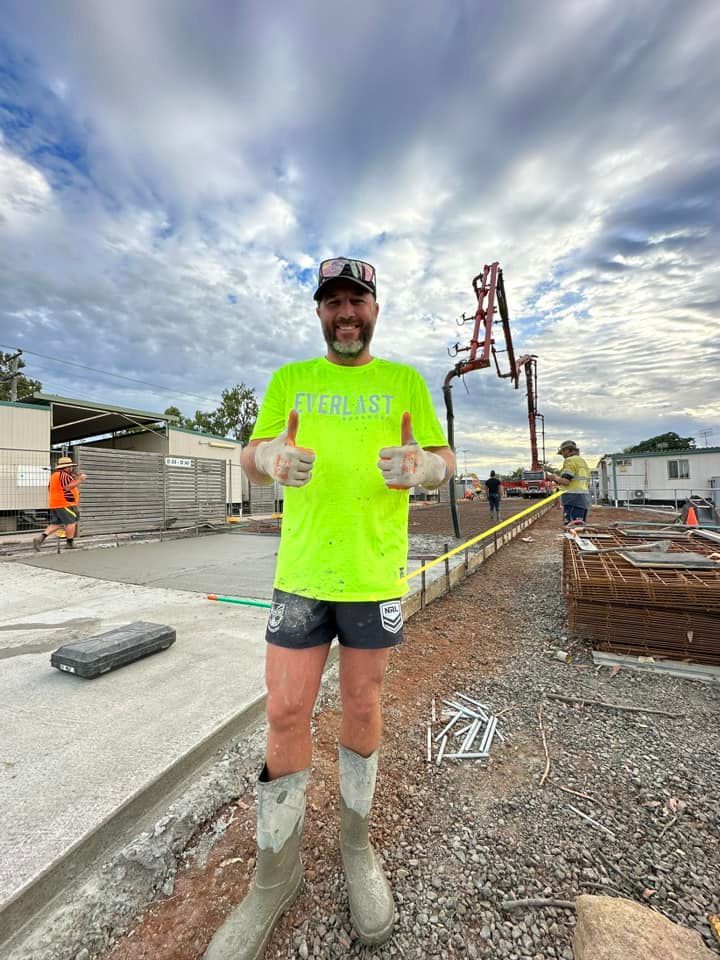 A man is standing on a construction site giving a thumbs up.