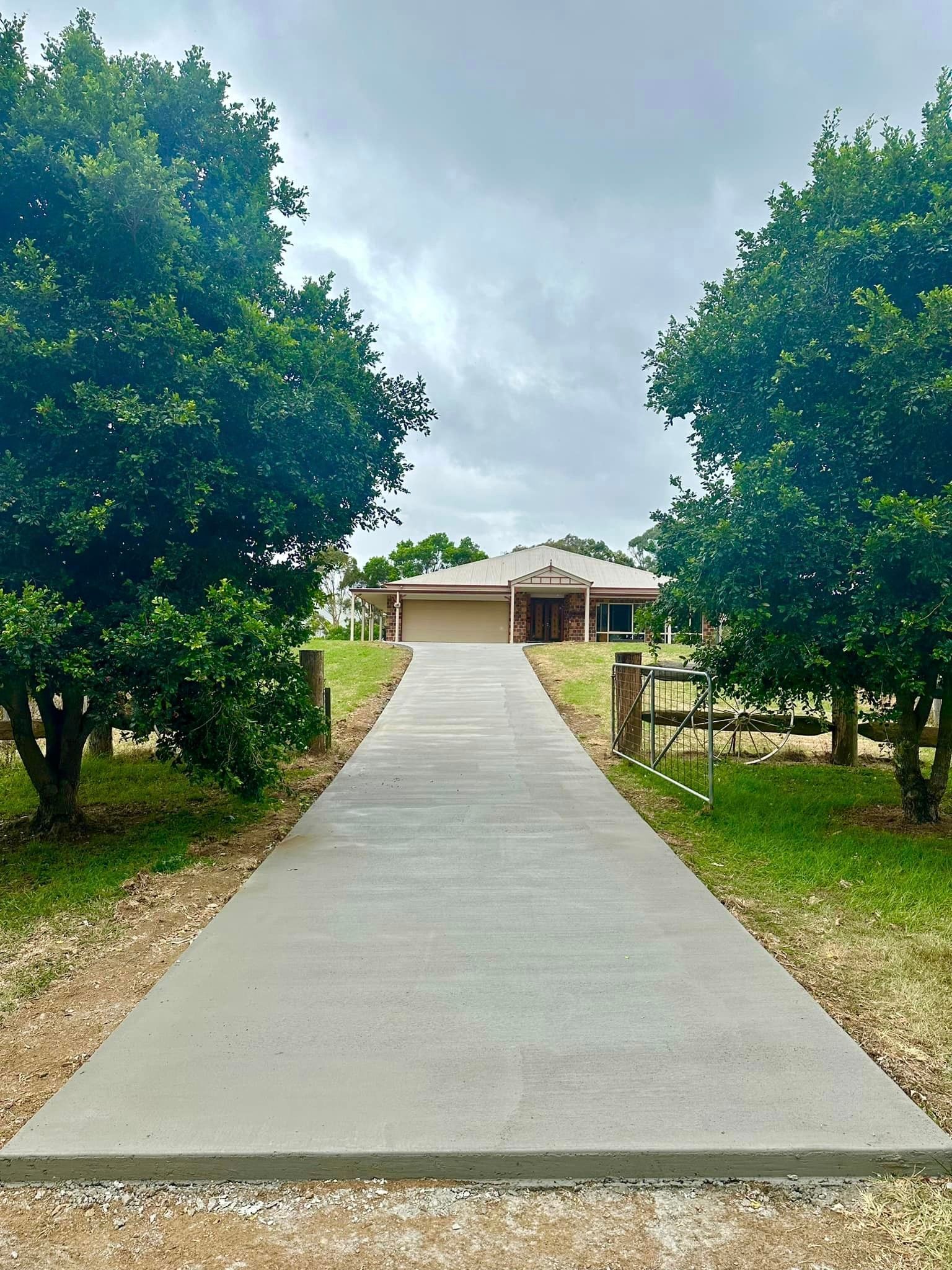 A concrete driveway leading to a house surrounded by trees.