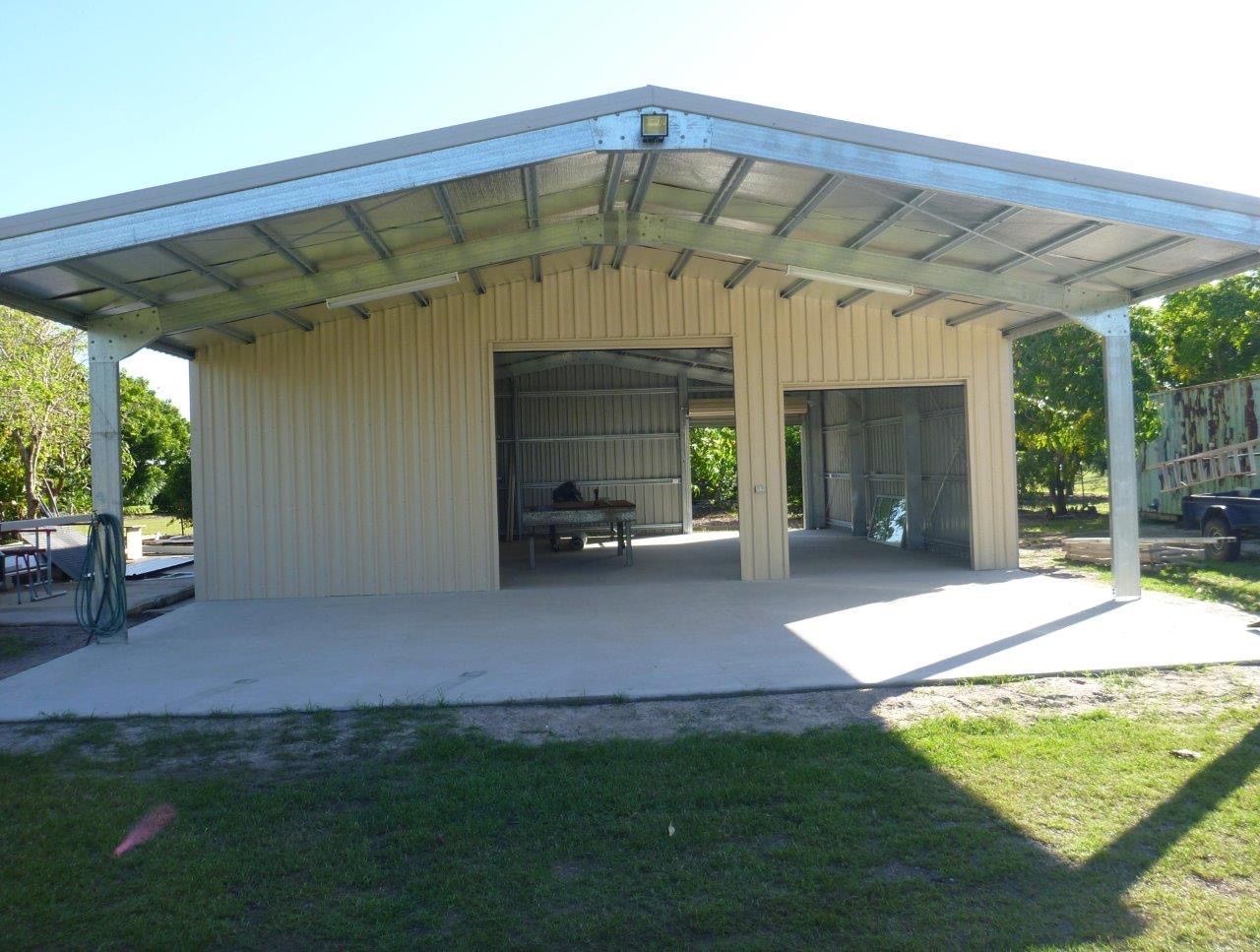 A large building with a metal roof is being built on a lush green field.