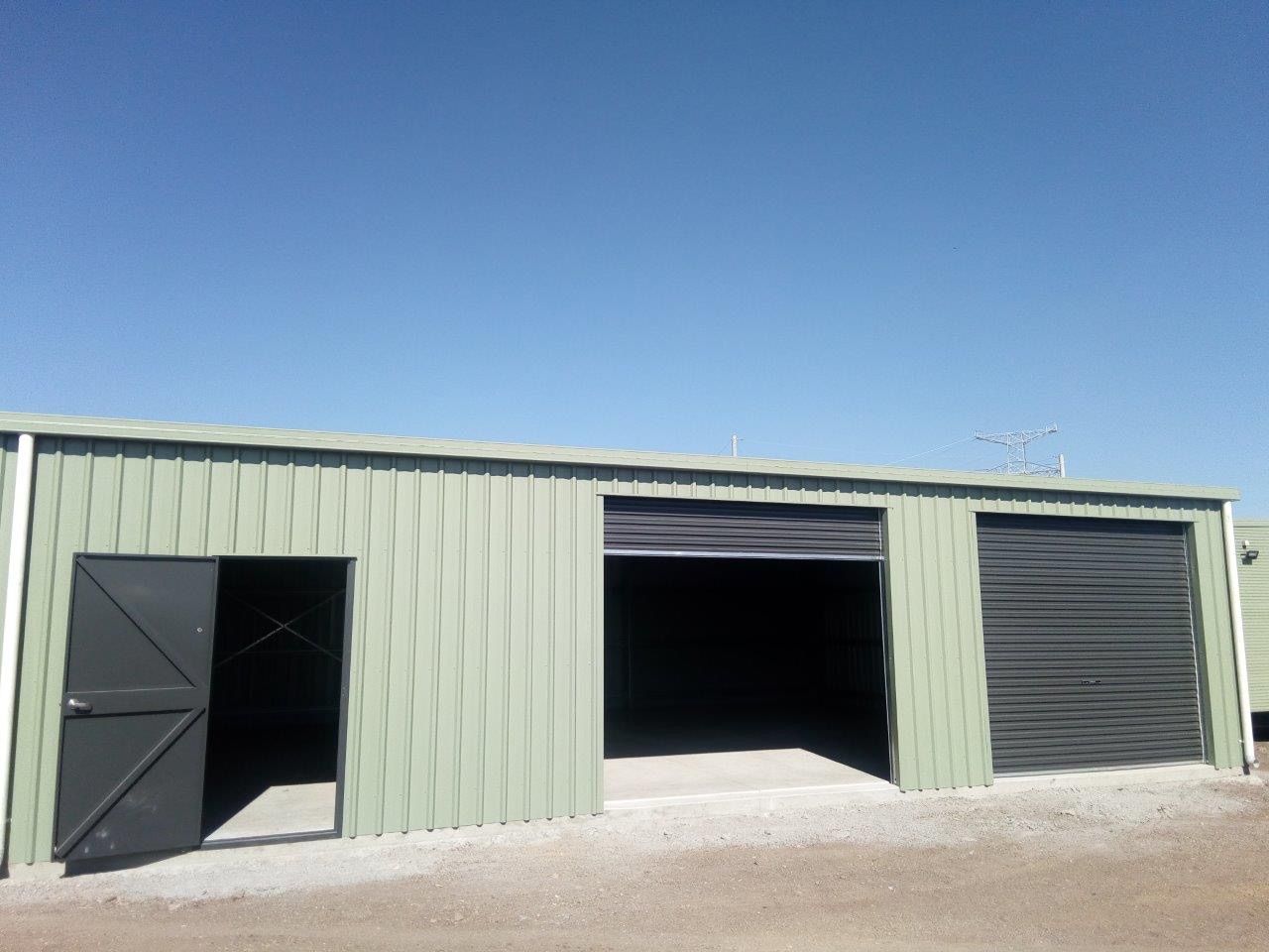 A green building with black doors and a blue sky in the background
