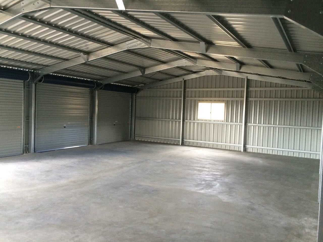 A large empty warehouse with a concrete floor and a roof.