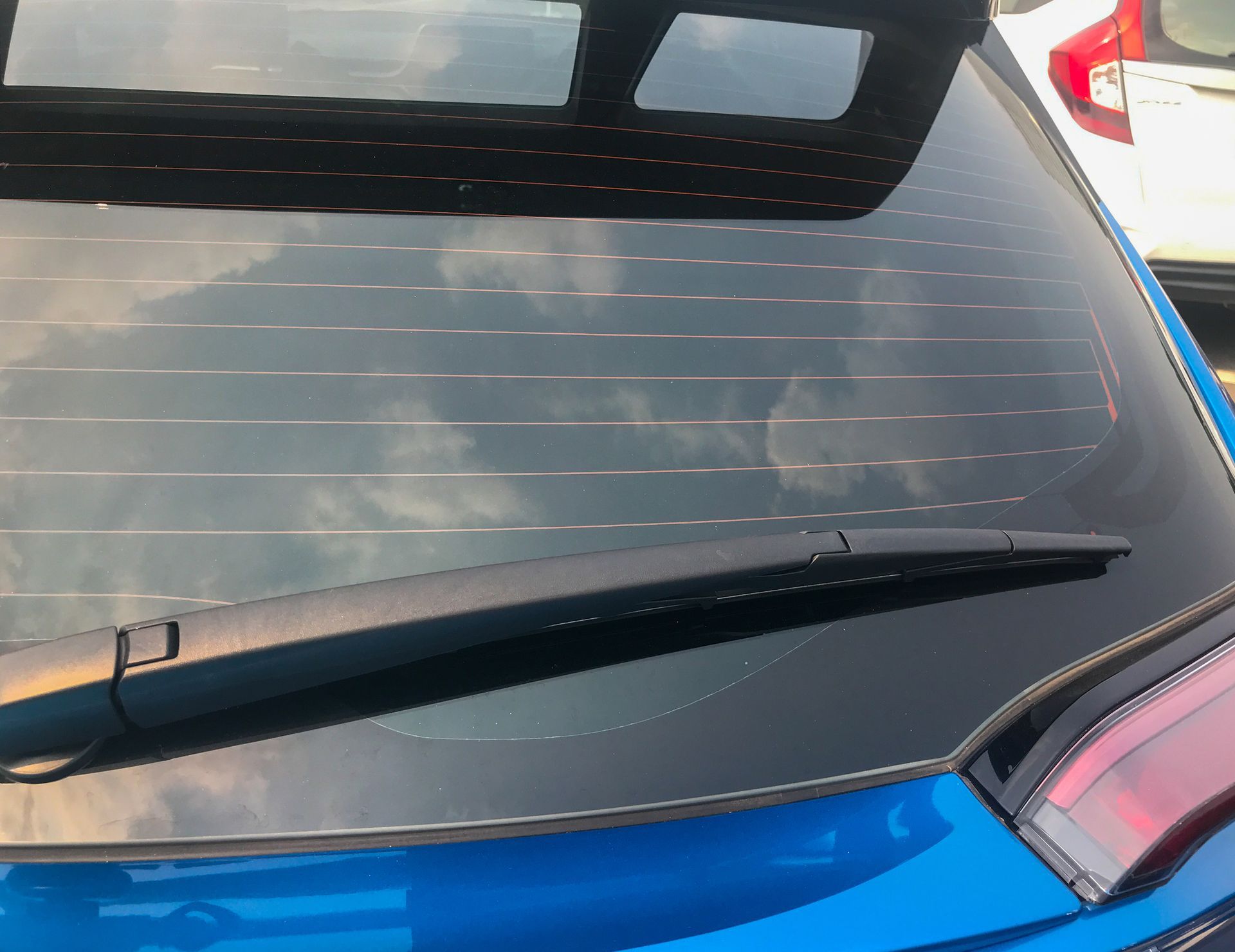 A blue car with a wiper on the back window
