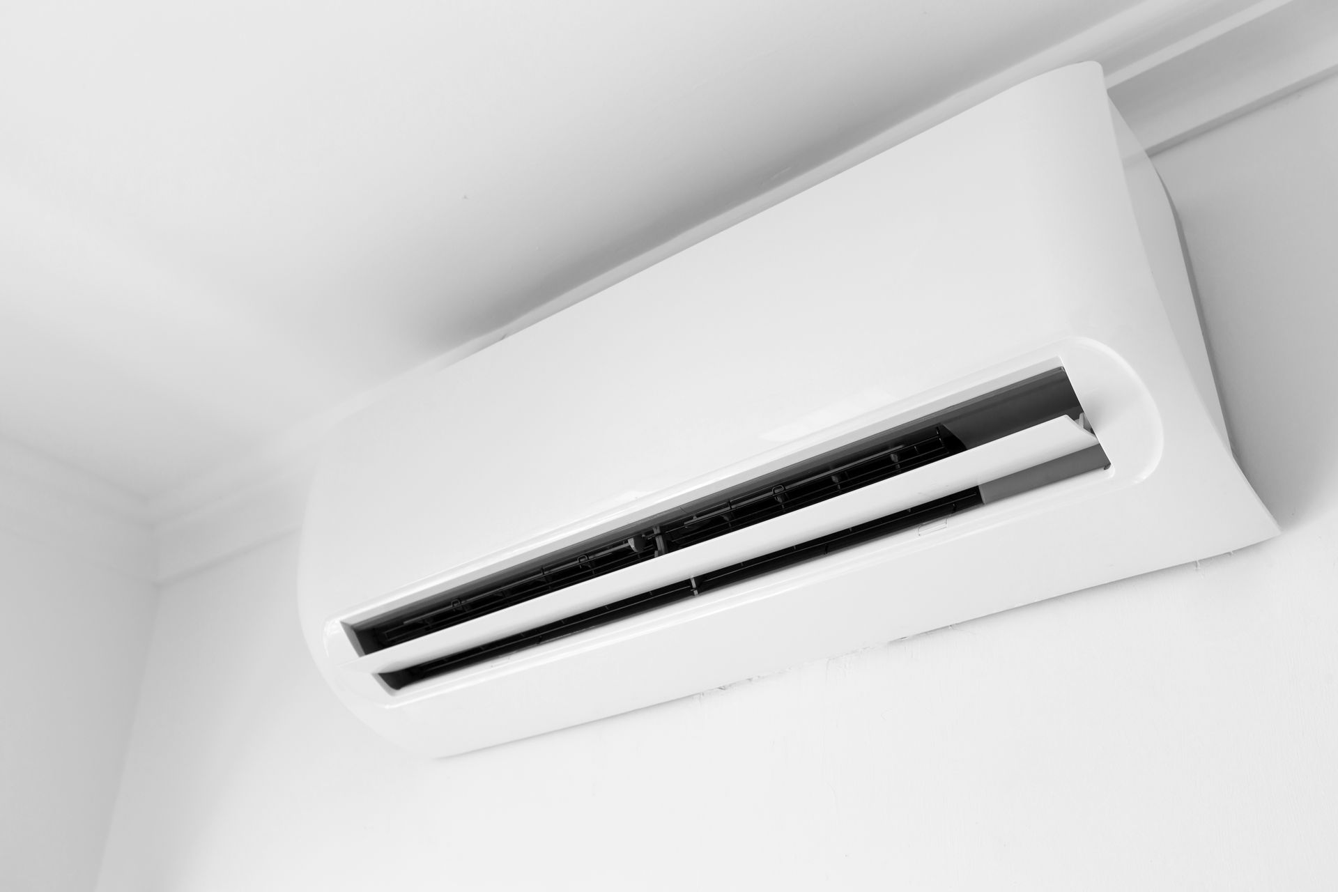 A white air conditioner is hanging from the ceiling in a room.