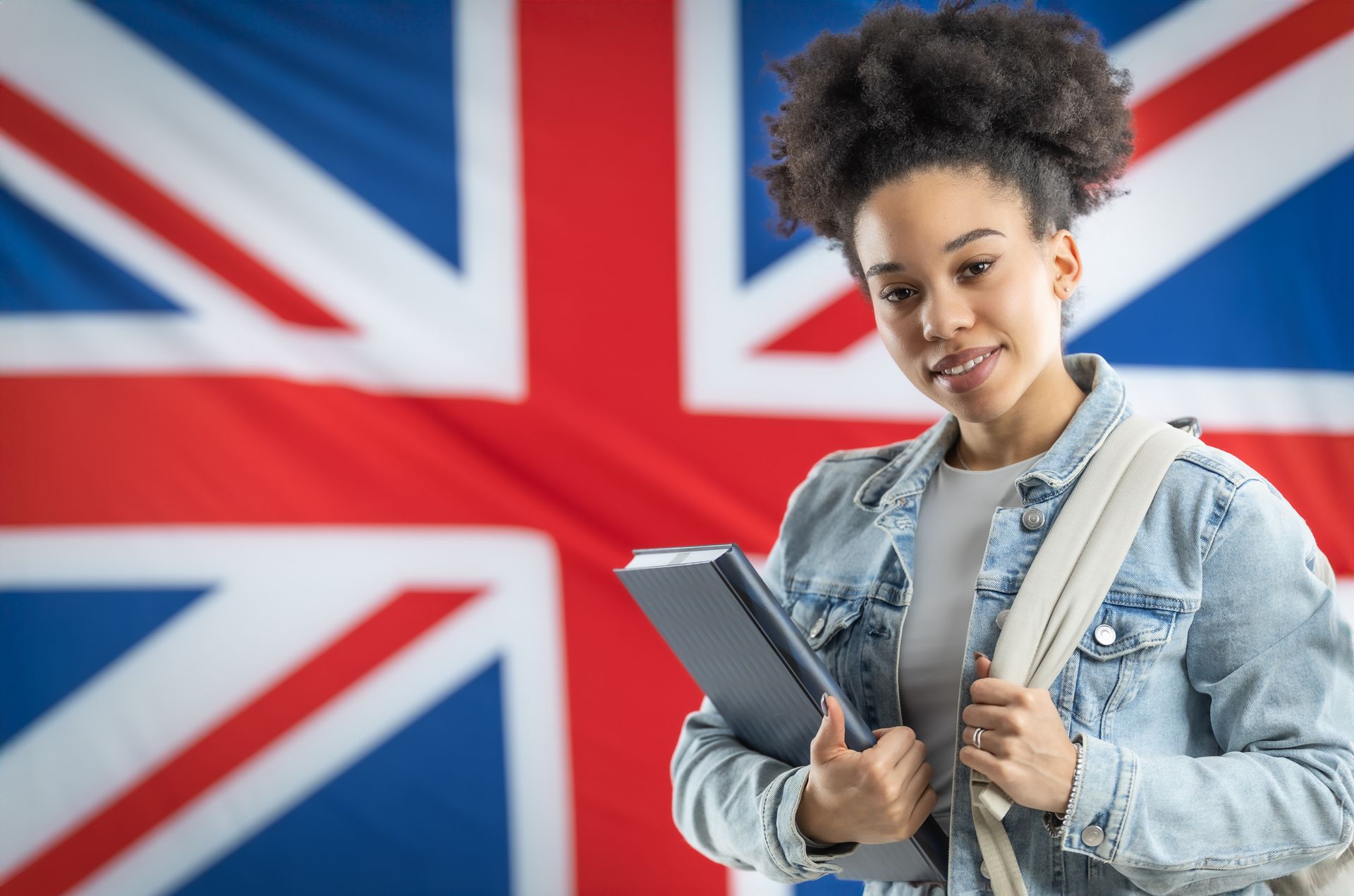 Una donna tiene in mano un tablet davanti a una bandiera britannica.