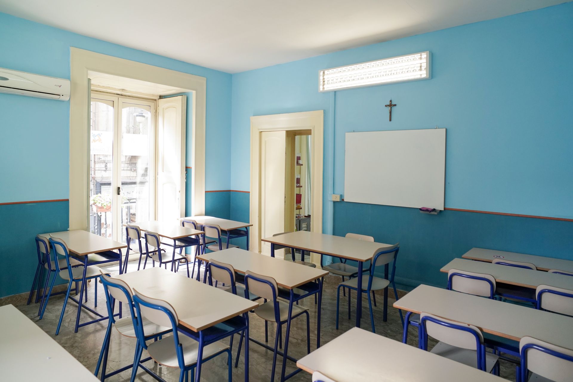 Un'aula con pareti blu e tavoli e sedie bianchi