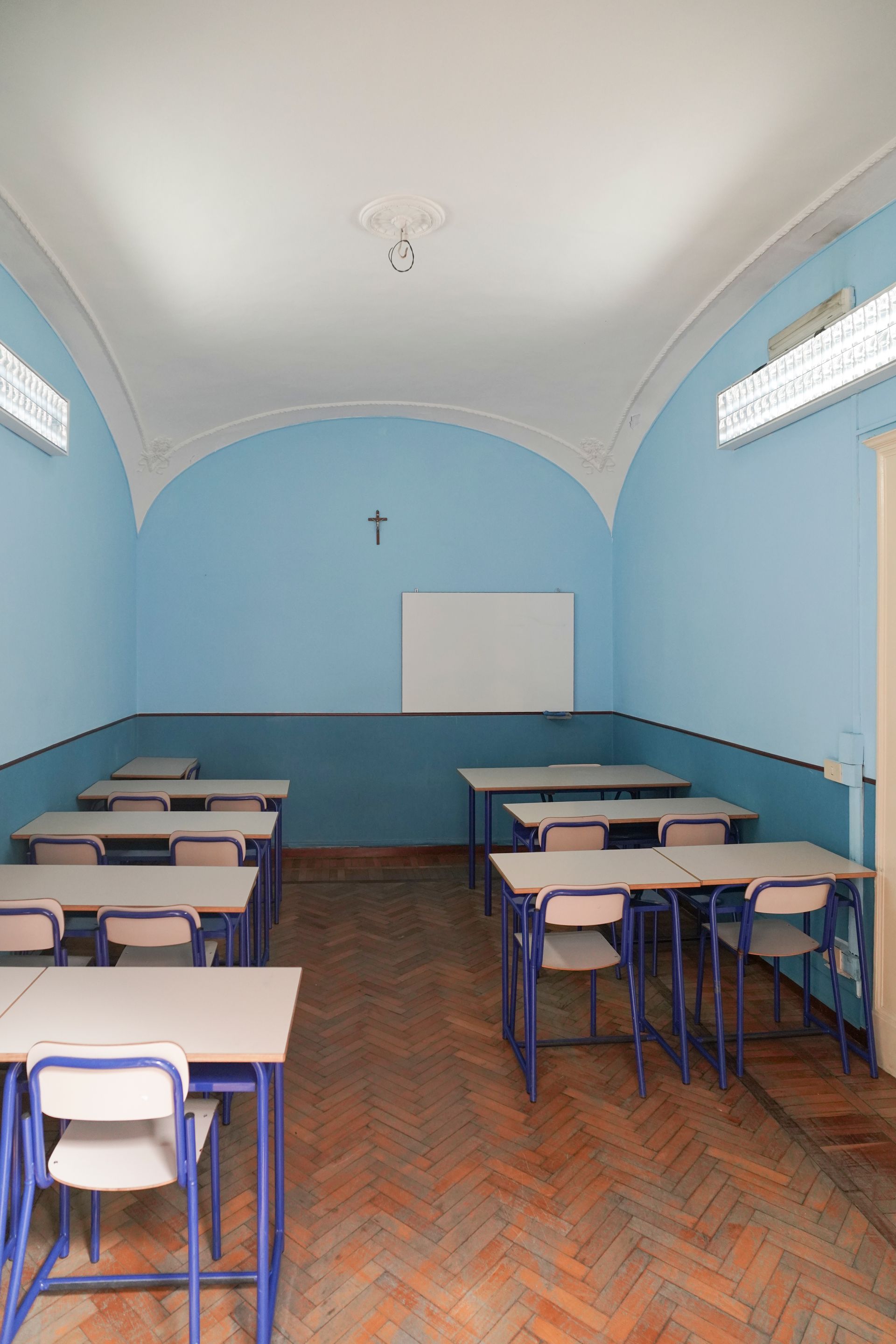 Un'aula con pareti blu e tavoli e sedie bianchi