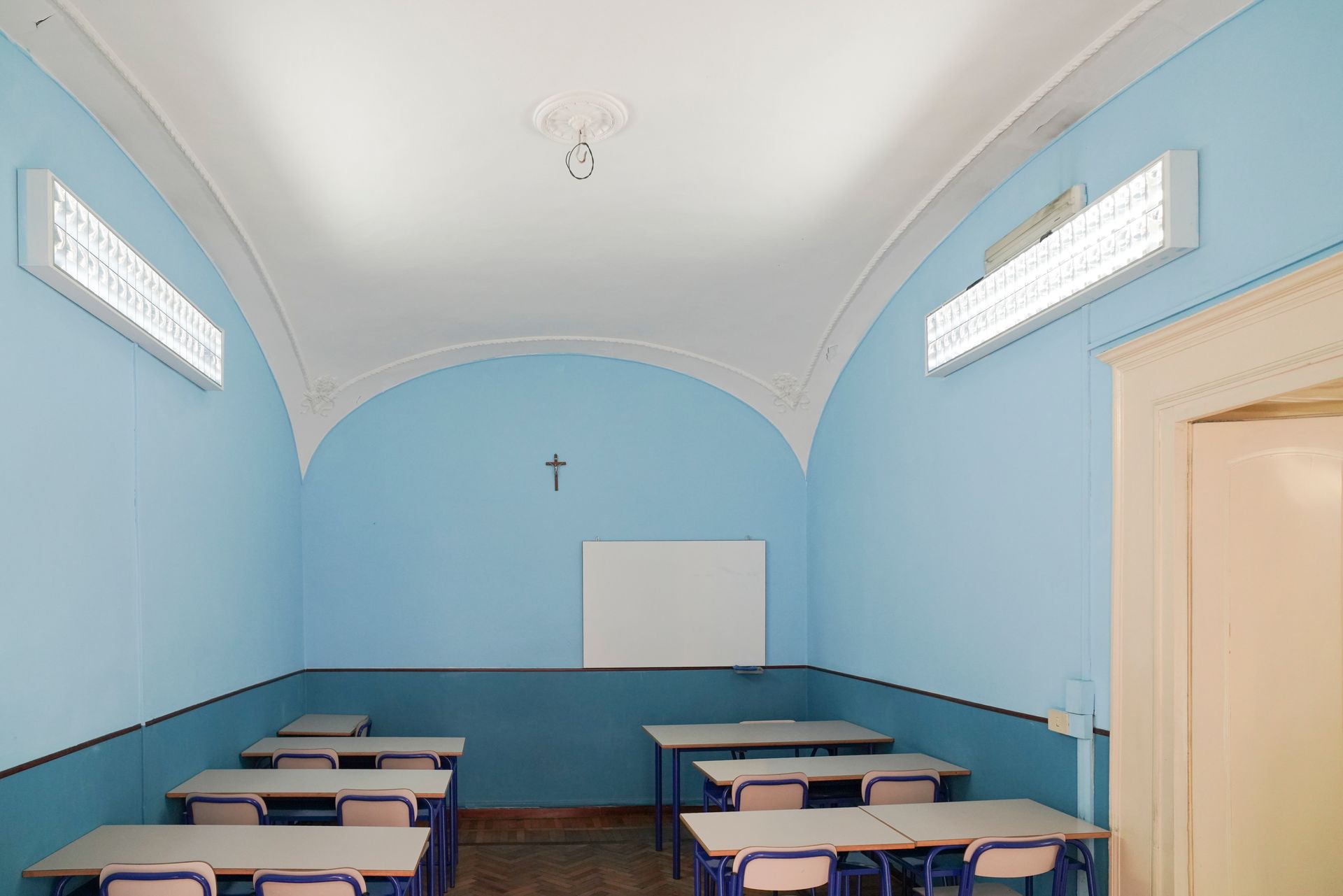 Un'aula con pareti blu e tavoli e sedie bianchi