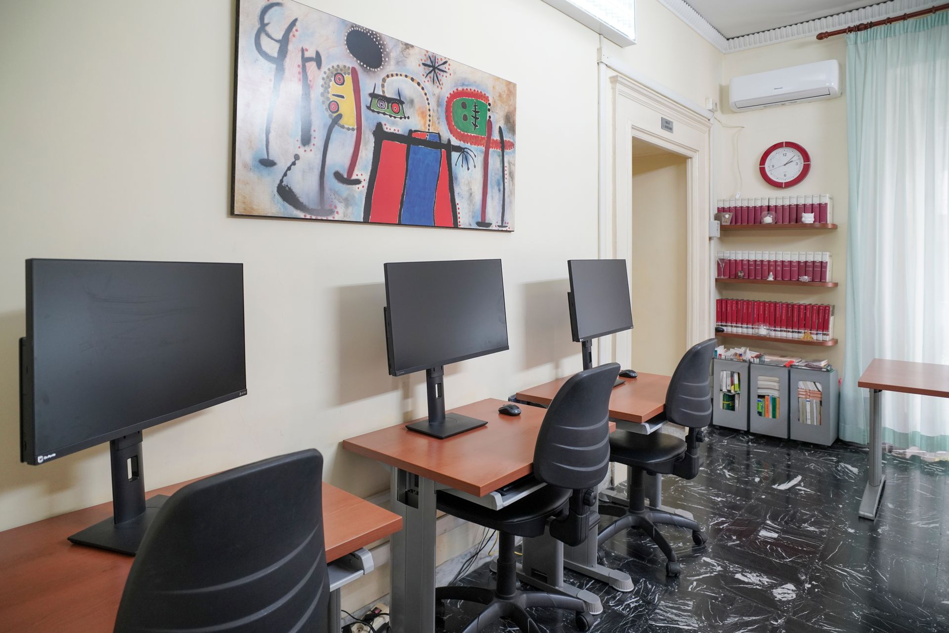 Una stanza con un orologio sul muro e un dipinto sul muro