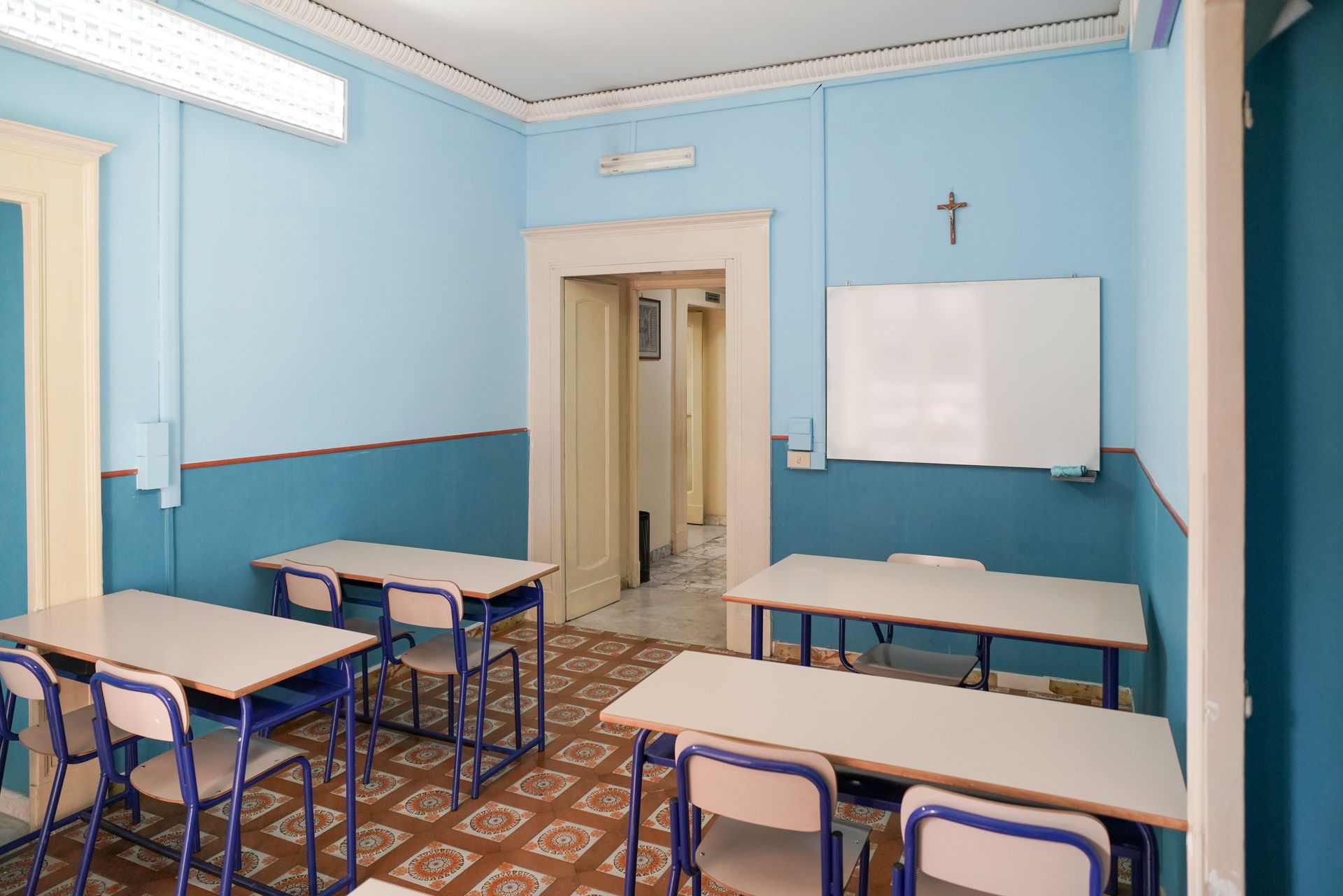 Un'aula con pareti blu e tavoli e sedie bianchi