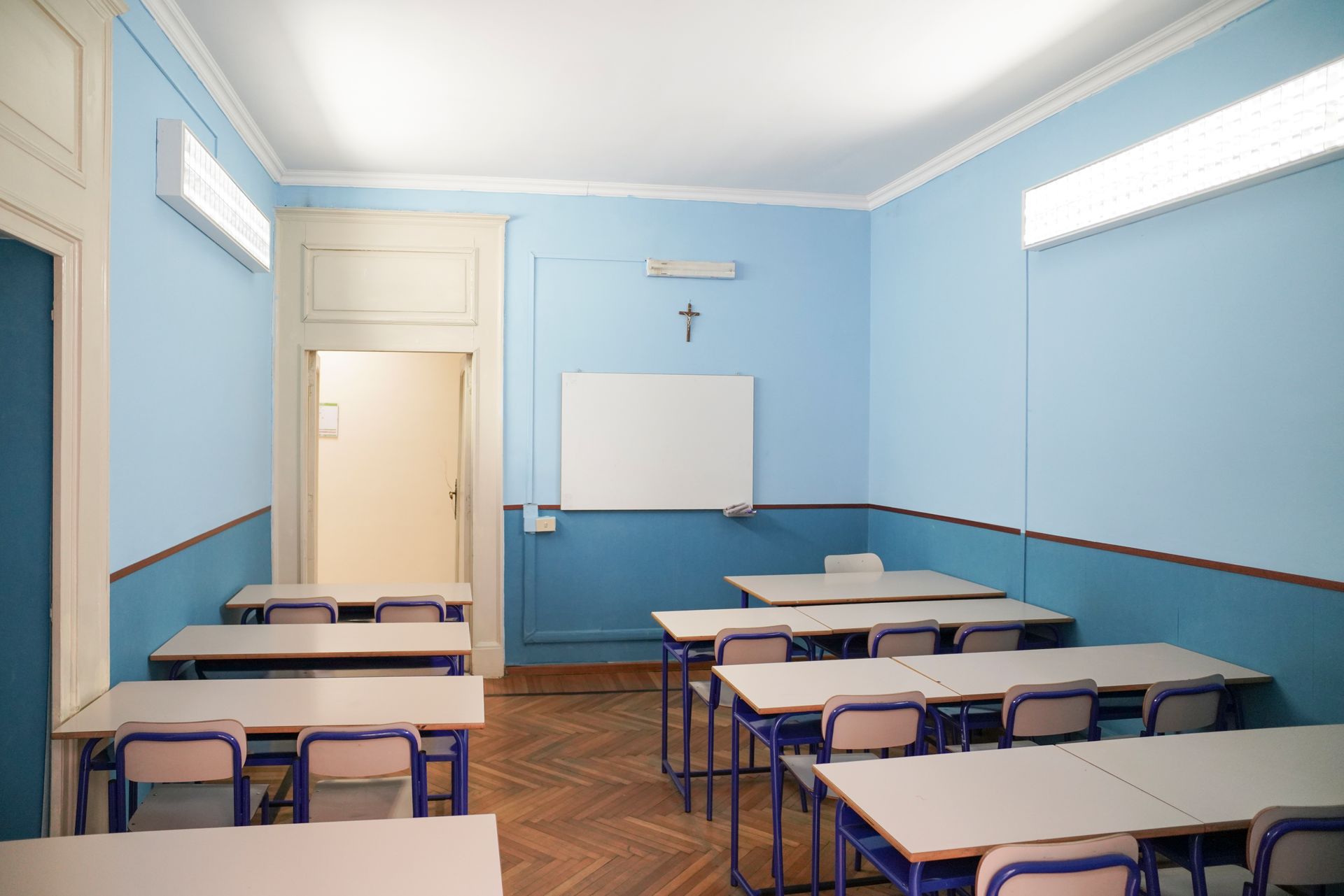 Un'aula con pareti blu e tavoli e sedie bianchi