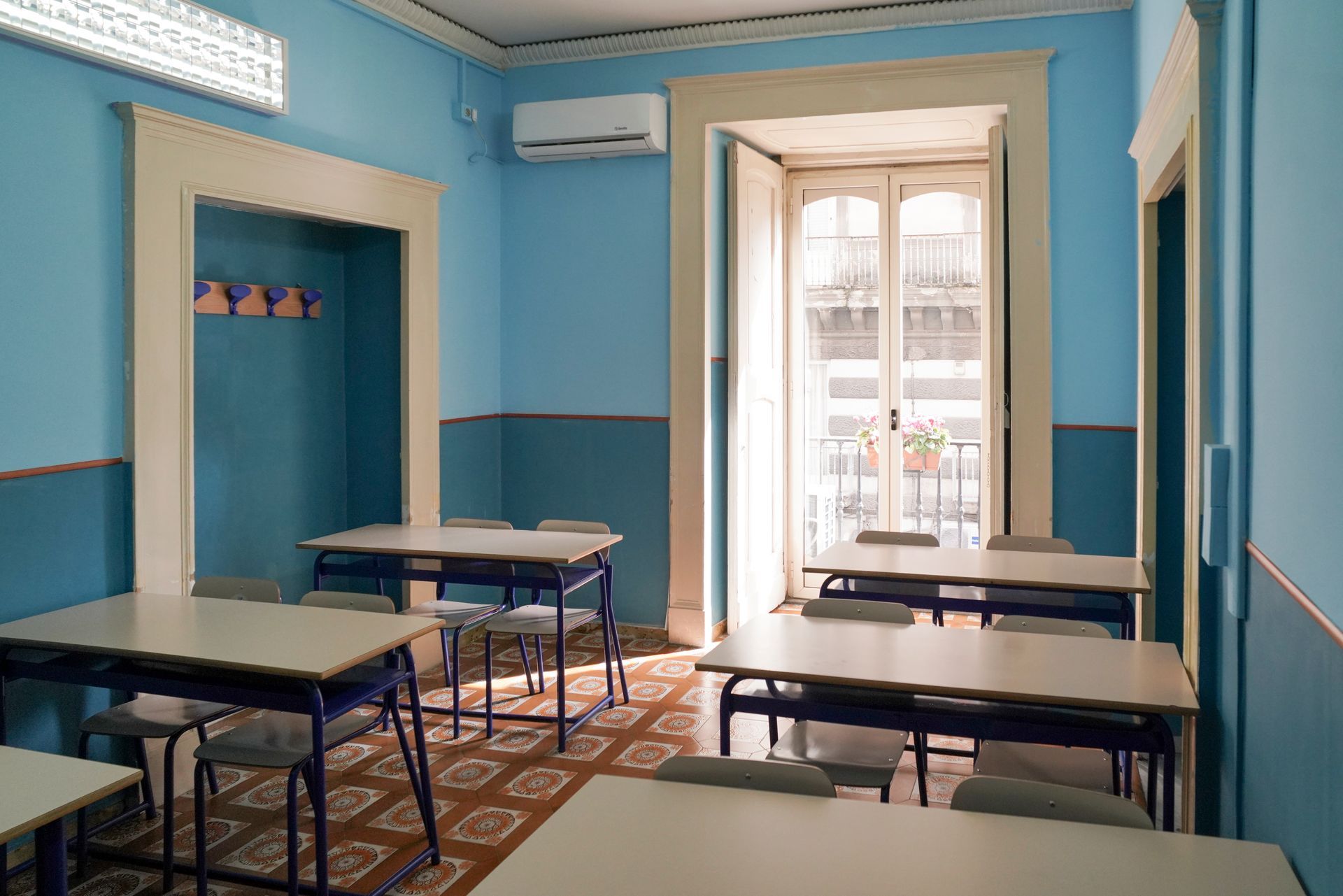 Un'aula con pareti blu e tavoli e sedie bianchi