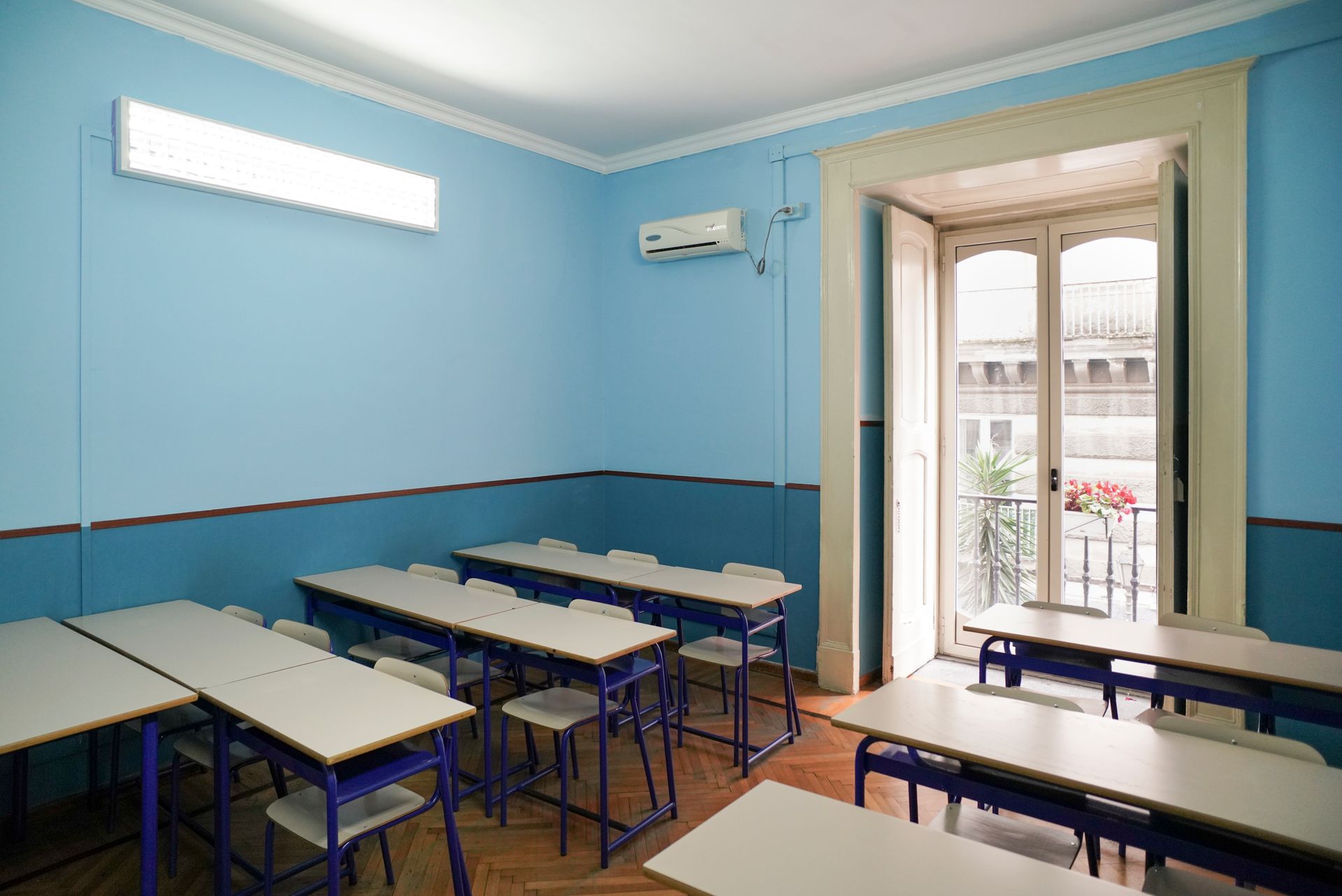 Un'aula con pareti blu e tavoli e sedie bianchi