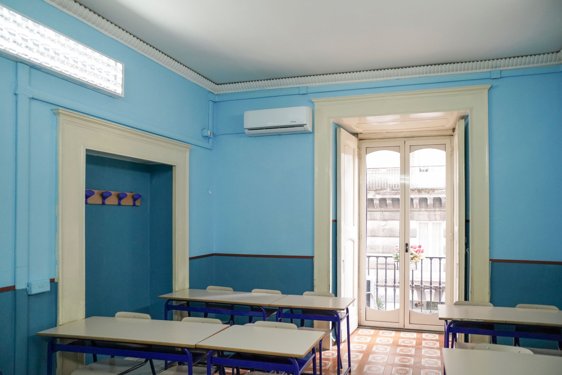 Un'aula con pareti blu e tavoli e sedie bianchi