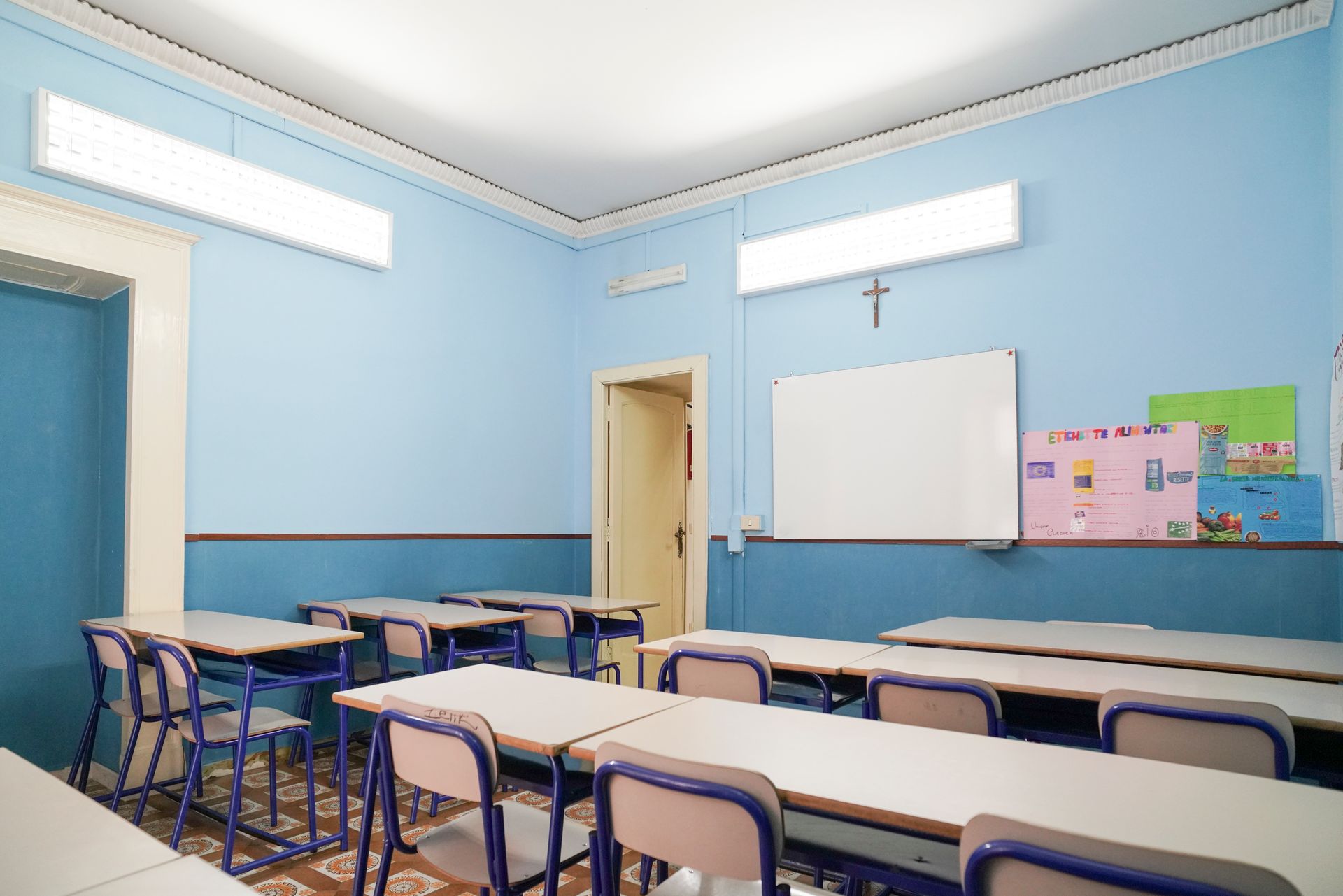 Un'aula con pareti blu e tavoli e sedie bianchi