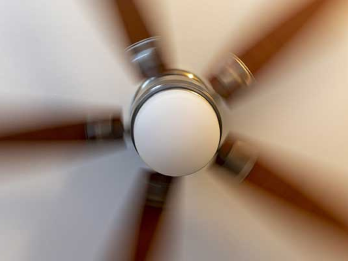 A close up of a ceiling fan spinning in a room.