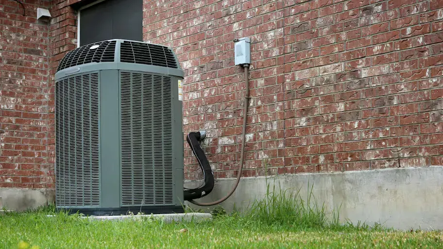 An air conditioner is sitting on the side of a brick building.