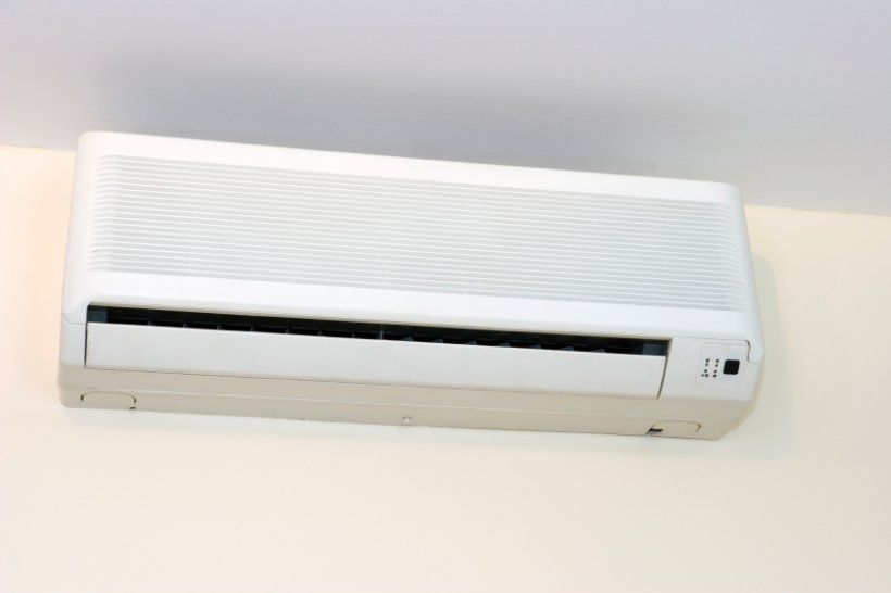 A white air conditioner is hanging on a white wall