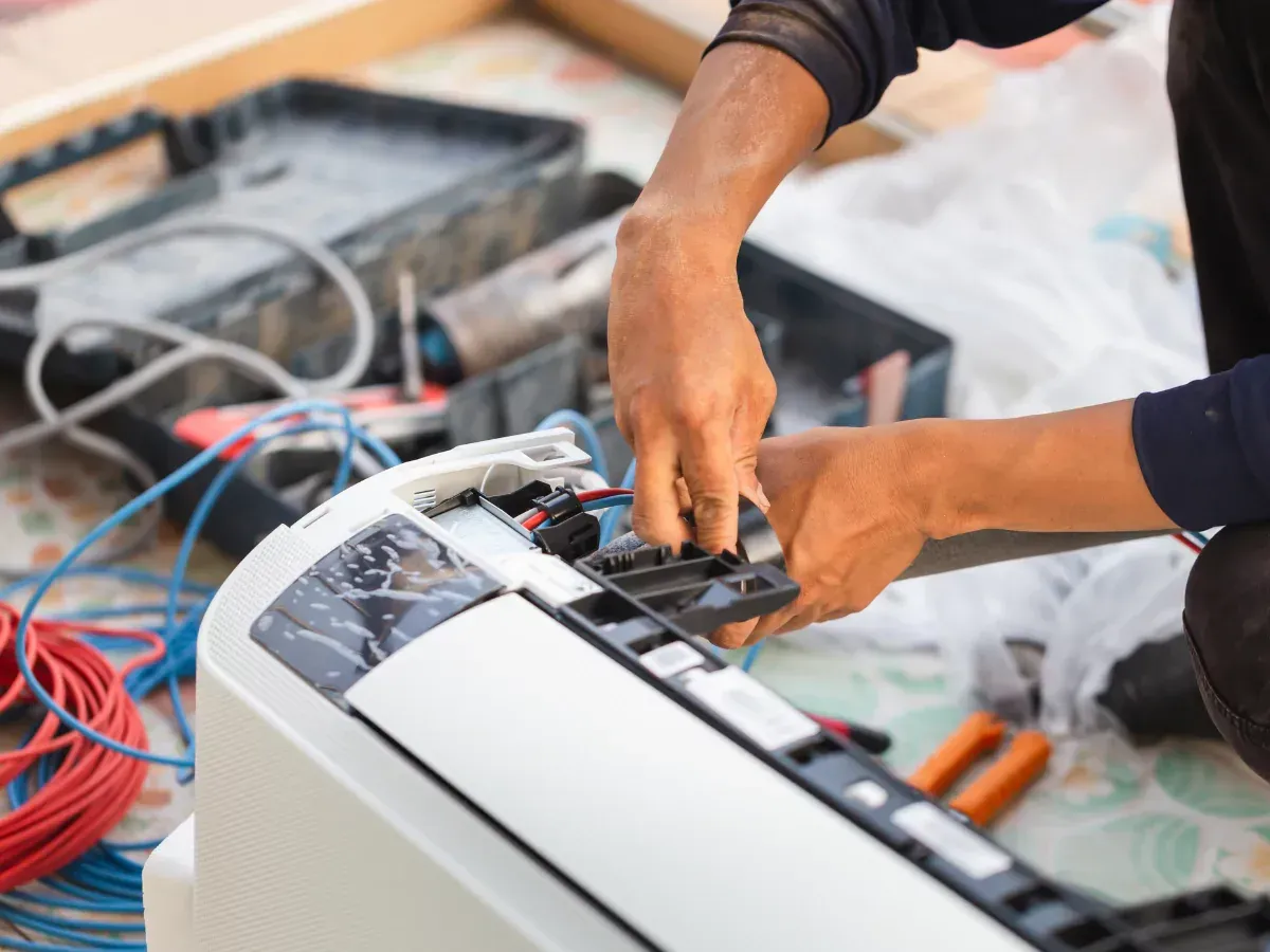 A man is fixing an air conditioner on the floor.