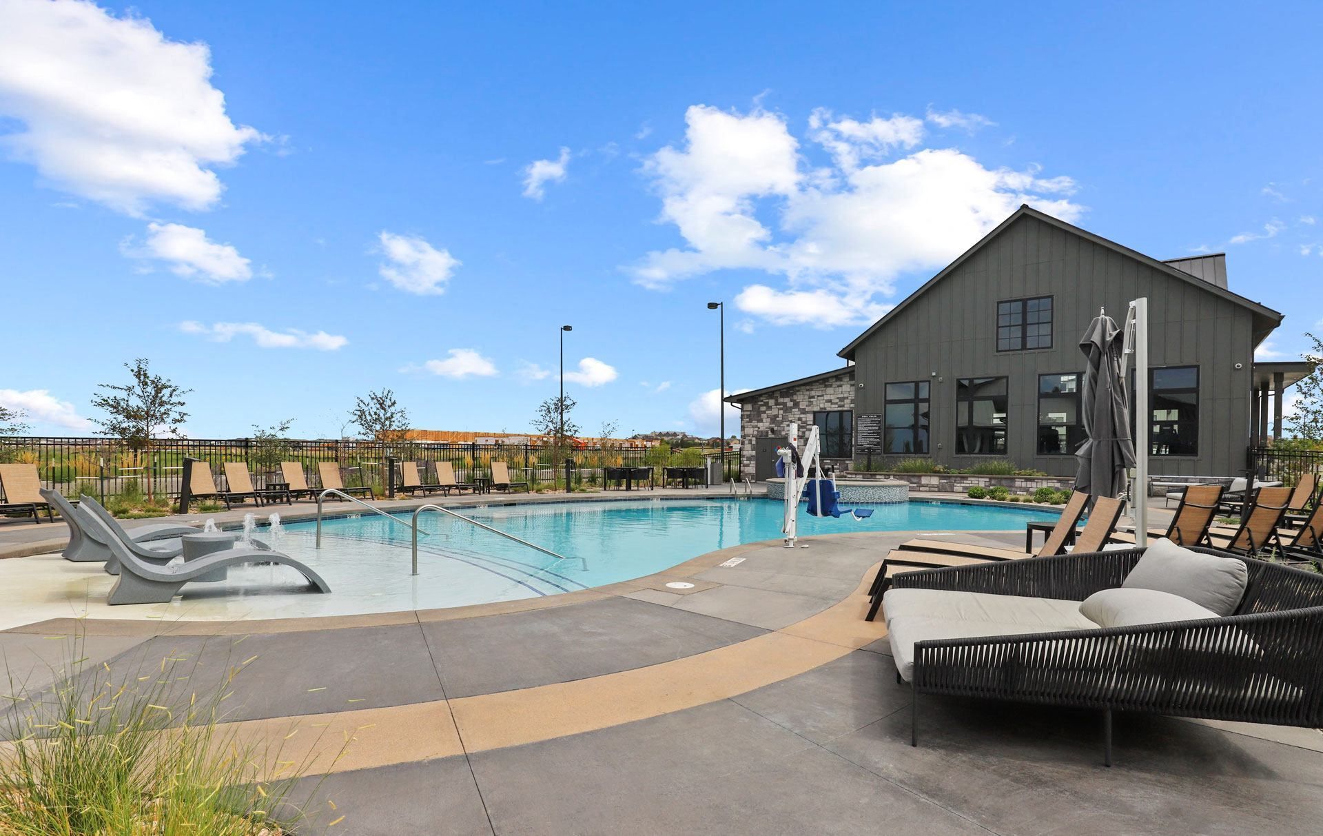 Outdoor swimming pool with lounge chairs beside a modern building under a blue sky