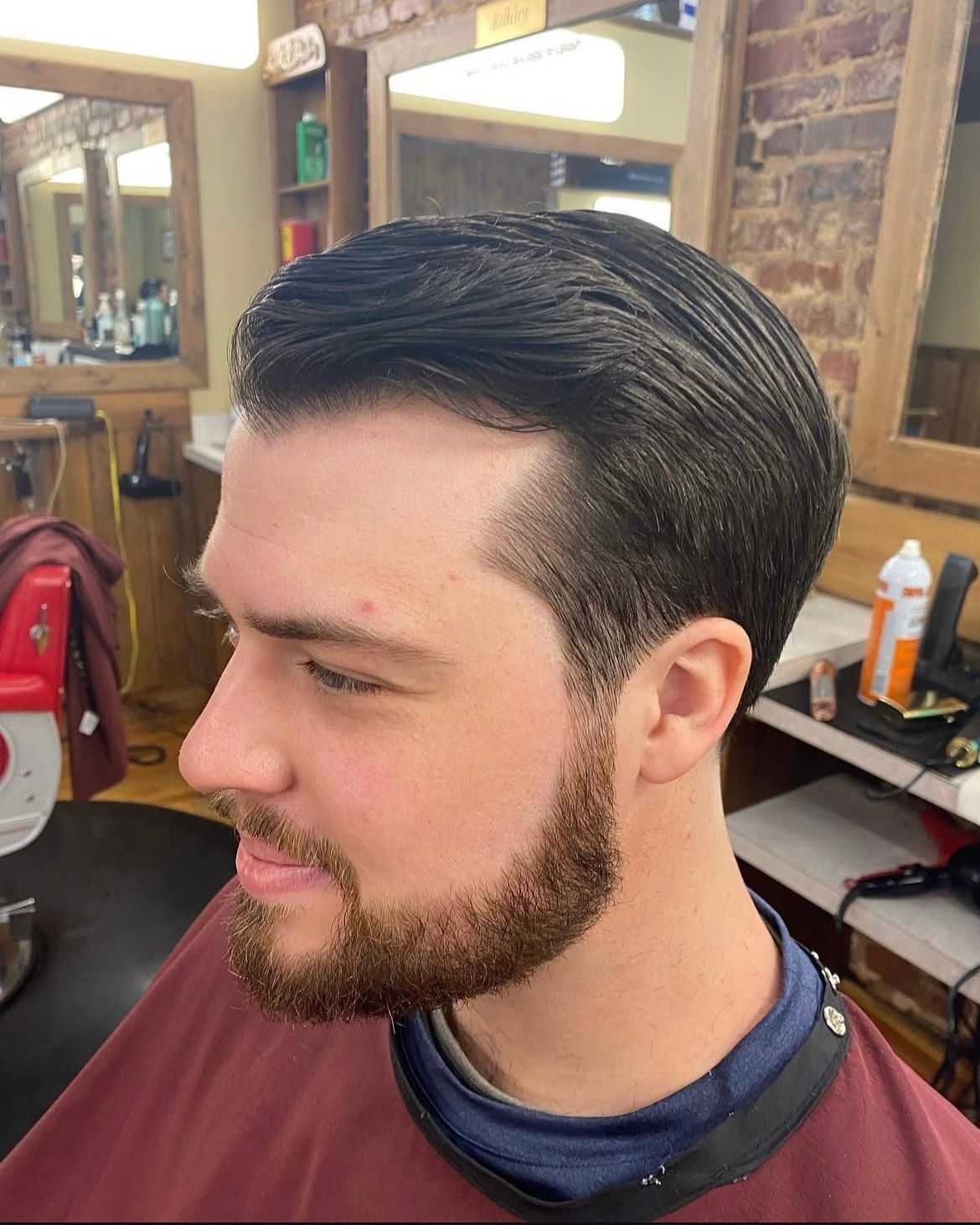 Man with dark hair and beard getting a haircut in a barbershop.