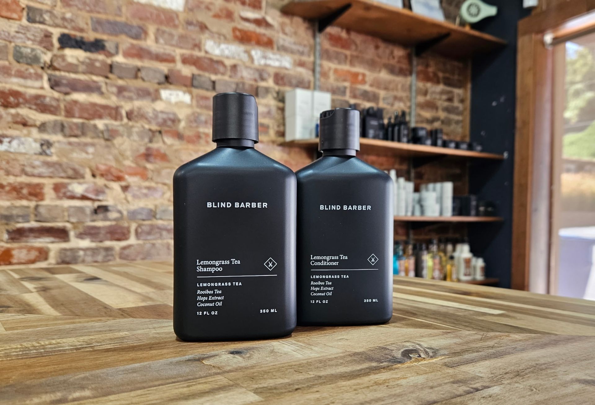 Three shaving brushes in black boxes, various handle styles, natural bristle color, on wooden shelf.