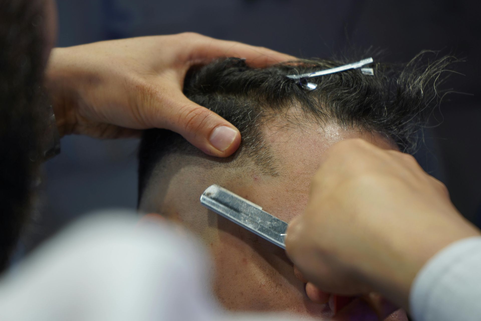 Man with shaved head and long gray beard in a barber chair, eyes closed. Wearing a maroon cape.