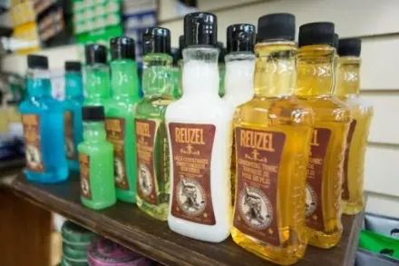 Bottles of Reuzel aftershave and grooming products in various colors displayed on a shelf.