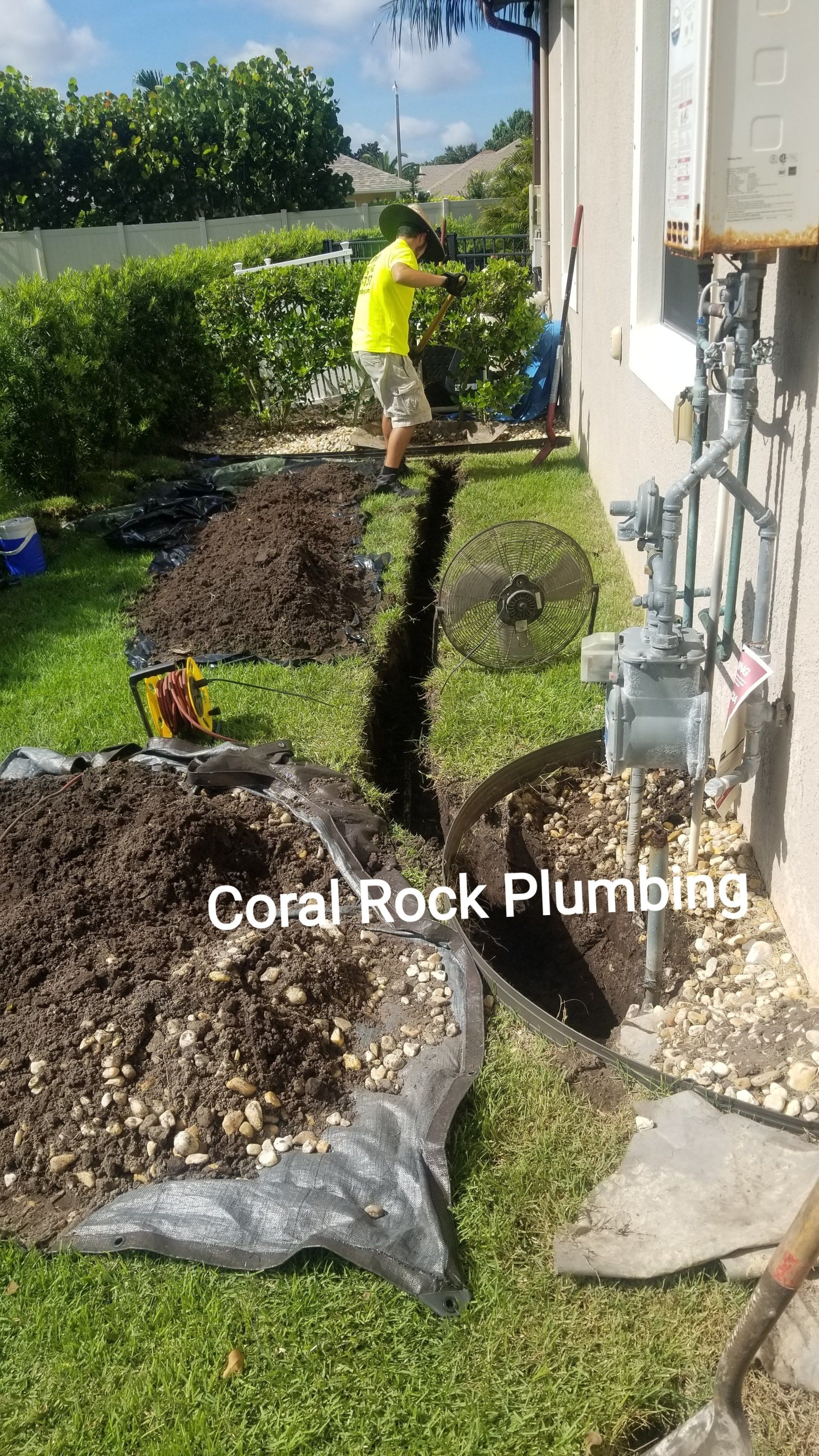 A man is digging a hole in the ground in front of a house.