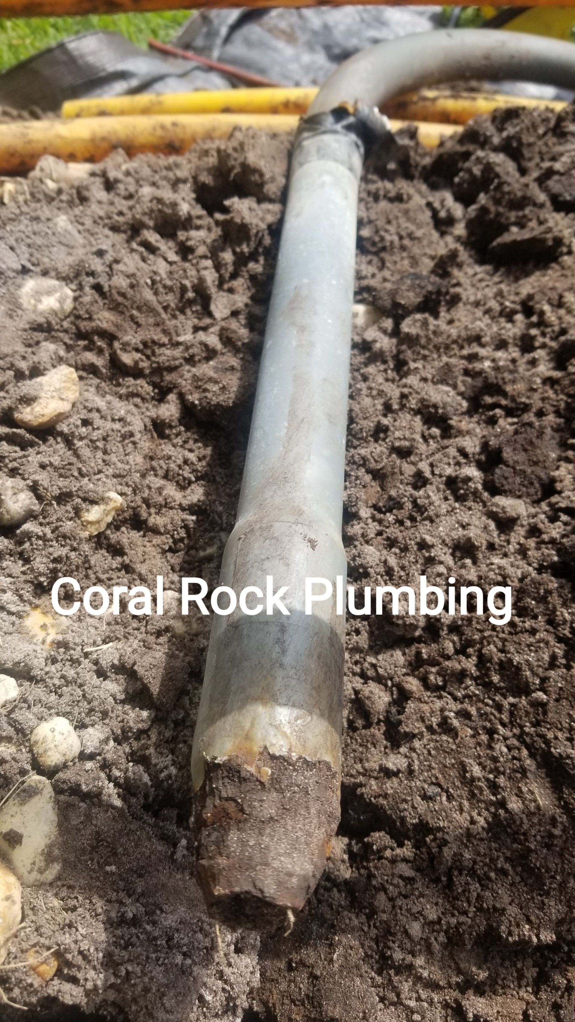 A coral rock plumbing pipe is laying in the dirt